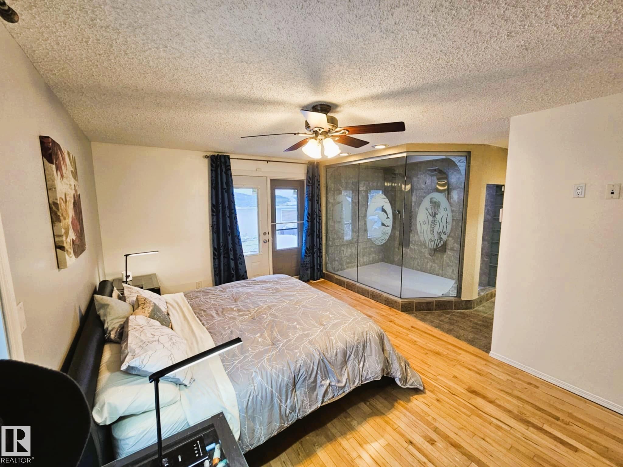 Bedroom featuring light wood-type flooring, access to outside, a textured ceiling, and a ceiling fan - 8512 131 Avenue, Edmonton, AB - Indoor Photo Showing Bedroom