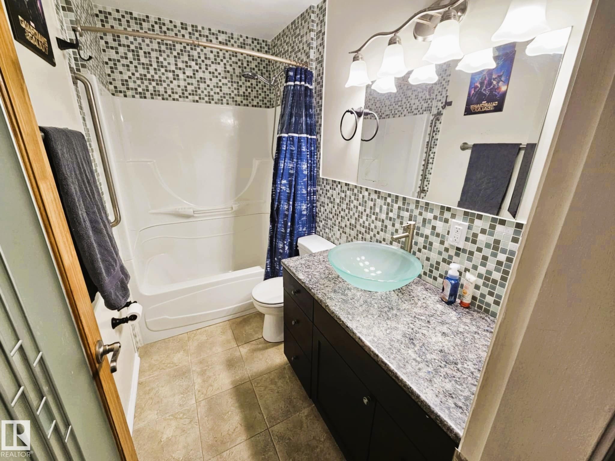 Full bathroom with vanity, shower / bathtub combination with curtain, decorative backsplash, and light tile patterned floors - 8512 131 Avenue, Edmonton, AB - Indoor Photo Showing Bathroom