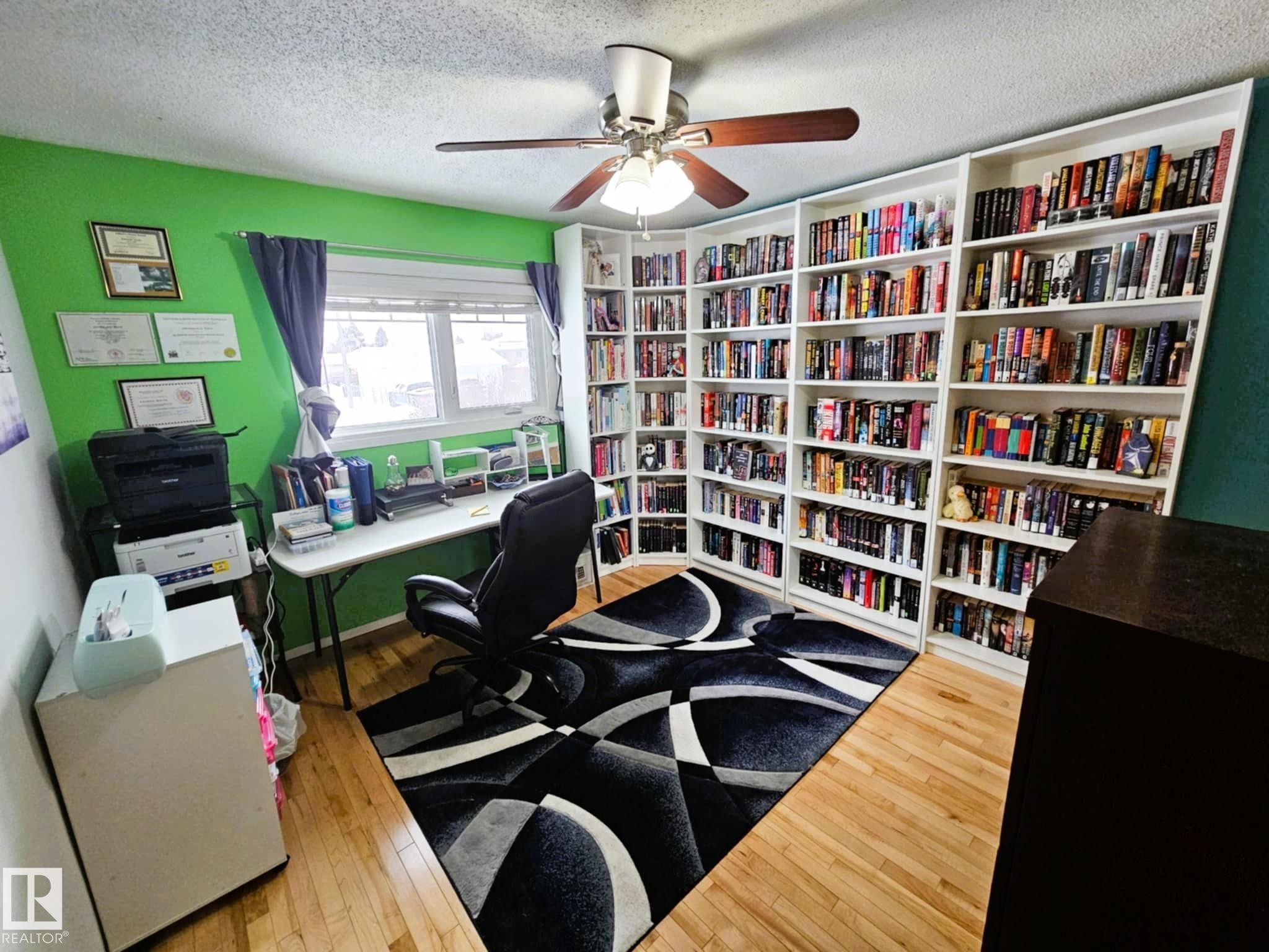 Office area with light wood-type flooring, ceiling fan, a textured ceiling, and wall of books - 8512 131 Avenue, Edmonton, AB - Indoor Photo Showing Office
