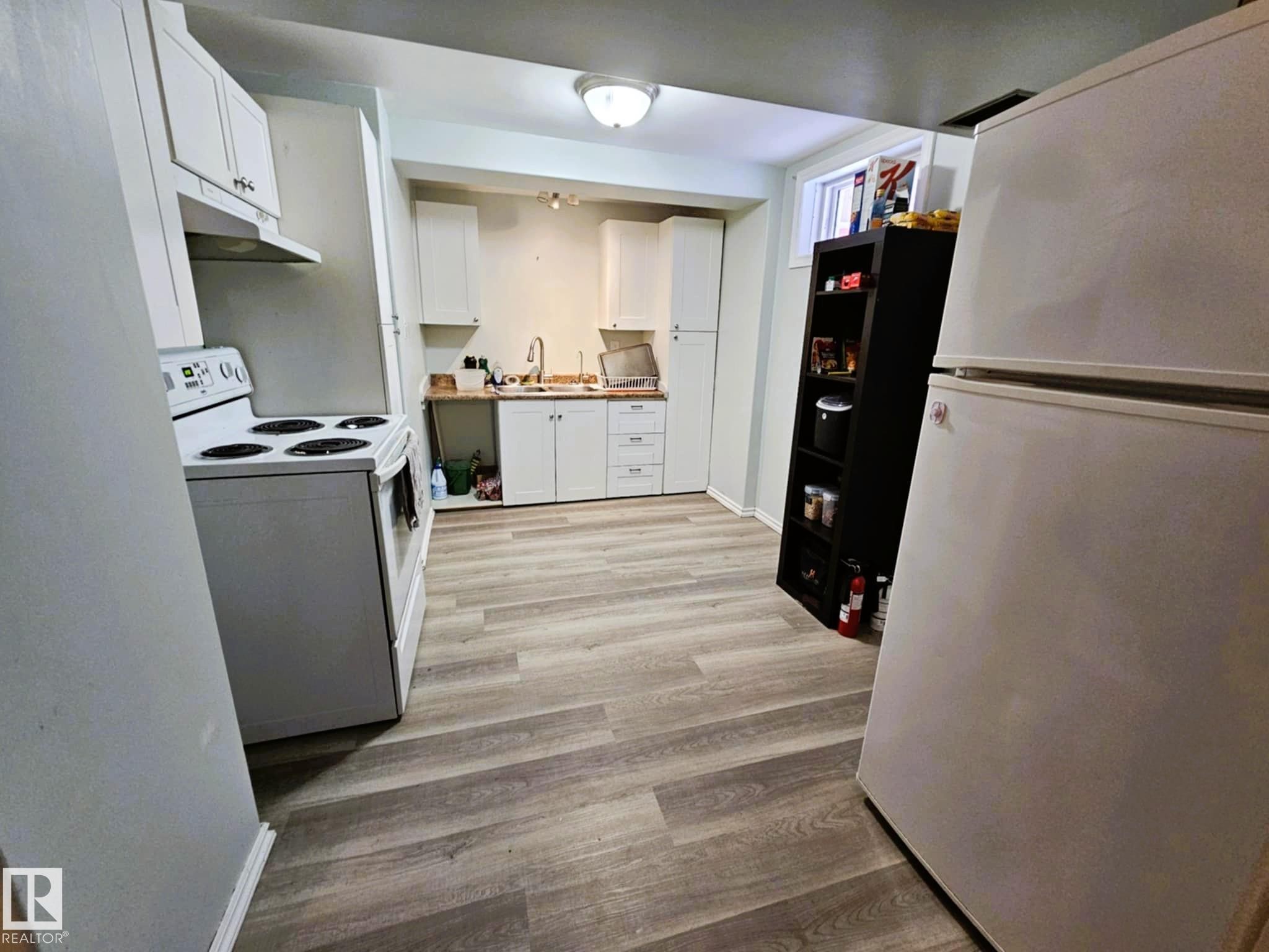 Kitchen featuring white appliances, white cabinetry, and light wood-style flooring - 8512 131 Avenue, Edmonton, AB - Indoor Photo Showing Other Room