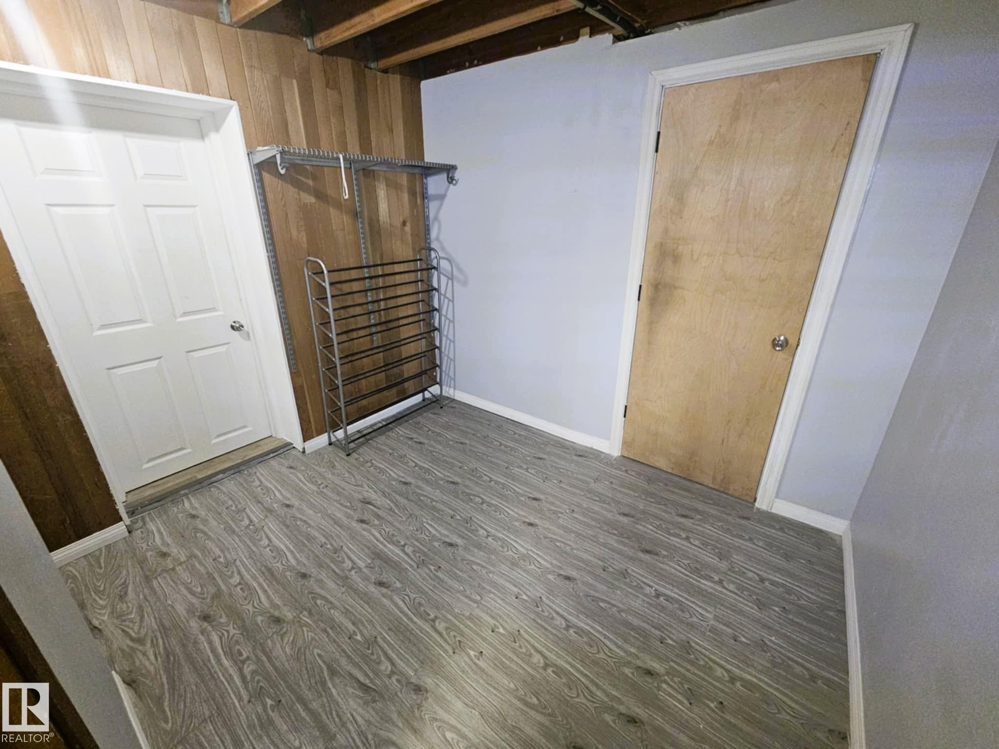 Unfurnished bedroom featuring light wood finished floors and wood walls - 8512 131 Avenue, Edmonton, AB - Indoor