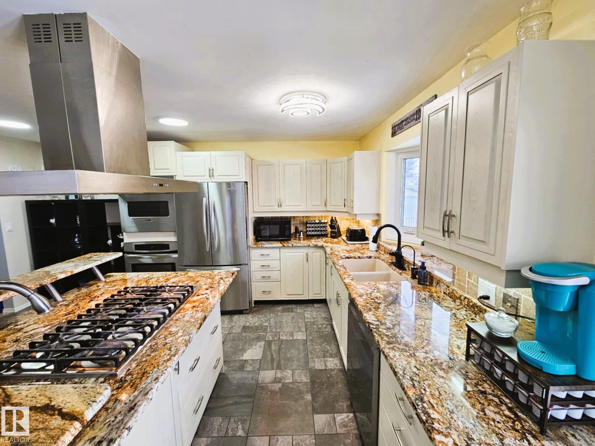 Kitchen with black appliances, island exhaust hood, light stone countertops, dark stone finish flooring, and white cabinetry - 8512 131 Avenue, Edmonton, AB - Indoor Photo Showing Kitchen With Double Sink With Upgraded Kitchen
