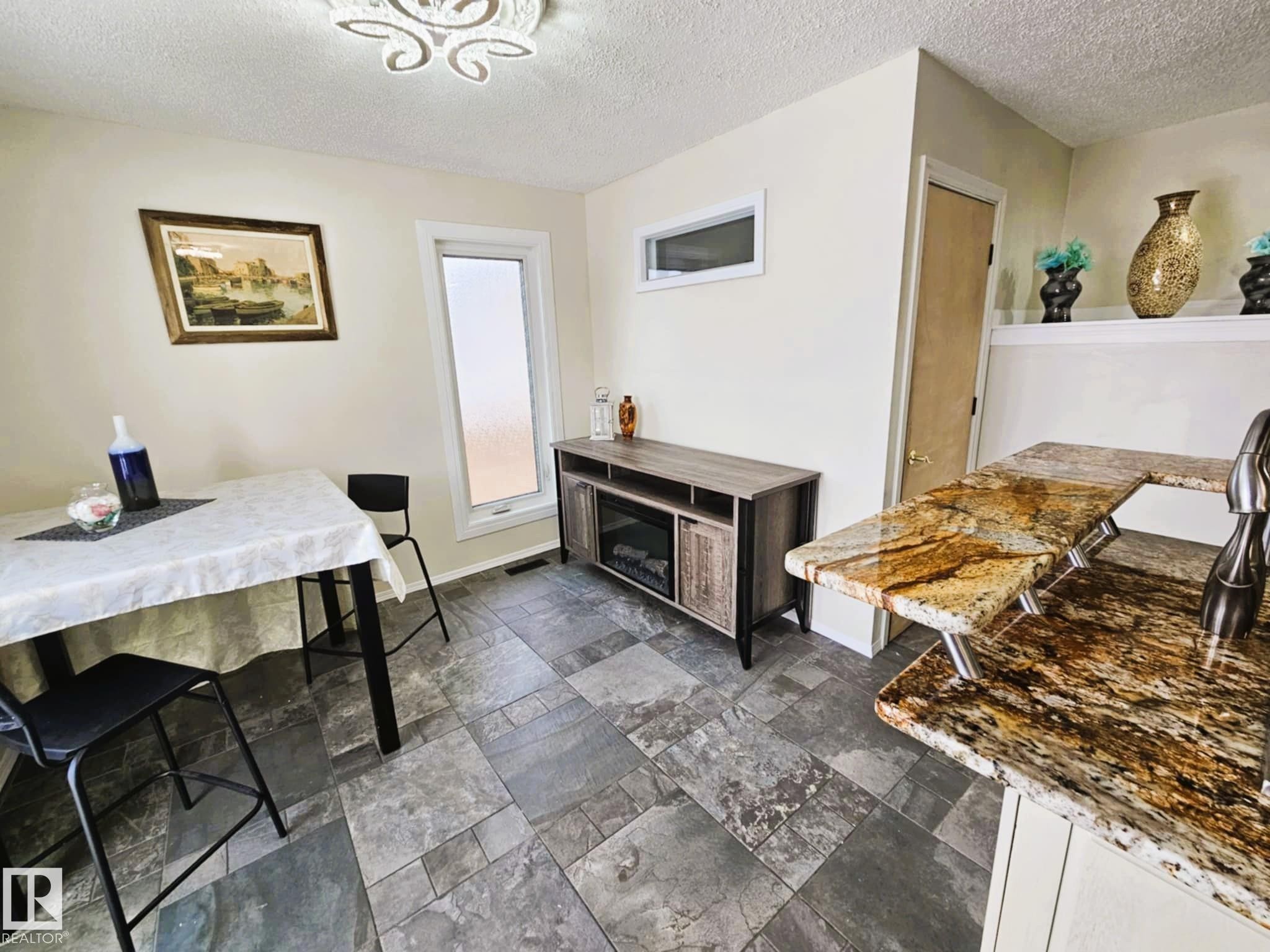 Dining room with a textured ceiling and stone tile floors - 8512 131 Avenue, Edmonton, AB - Indoor