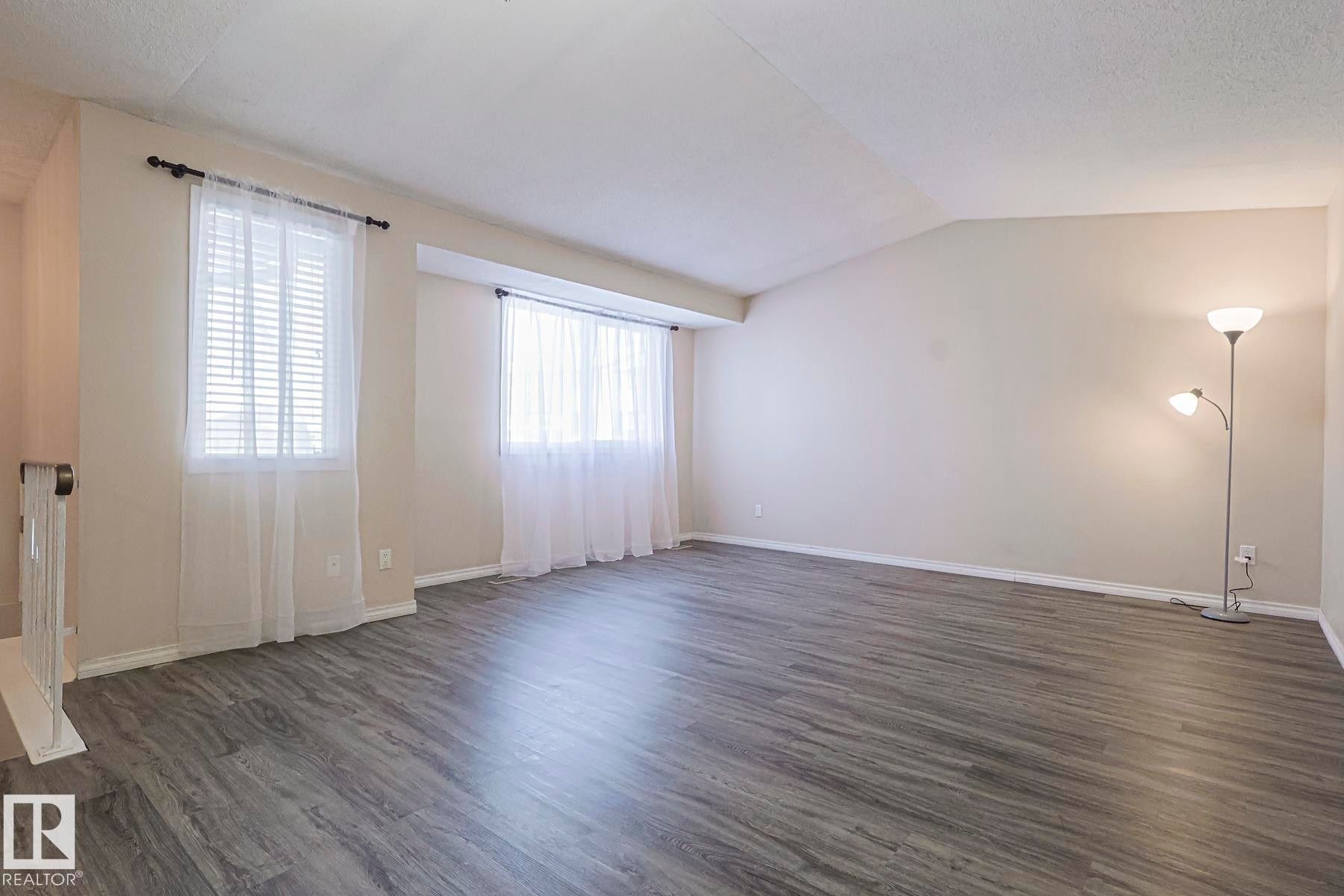 Empty room featuring dark wood-type flooring and vaulted ceiling - 1526 69 Street Nw, Edmonton, AB - Indoor Photo Showing Other Room