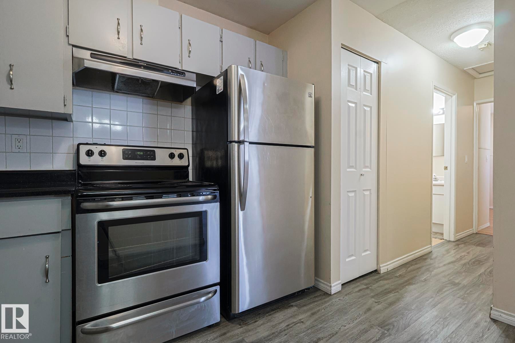 Kitchen featuring stainless steel appliances, dark countertops, decorative backsplash, and dark wood-style floors - 1526 69 Street Nw, Edmonton, AB - Indoor Photo Showing Kitchen