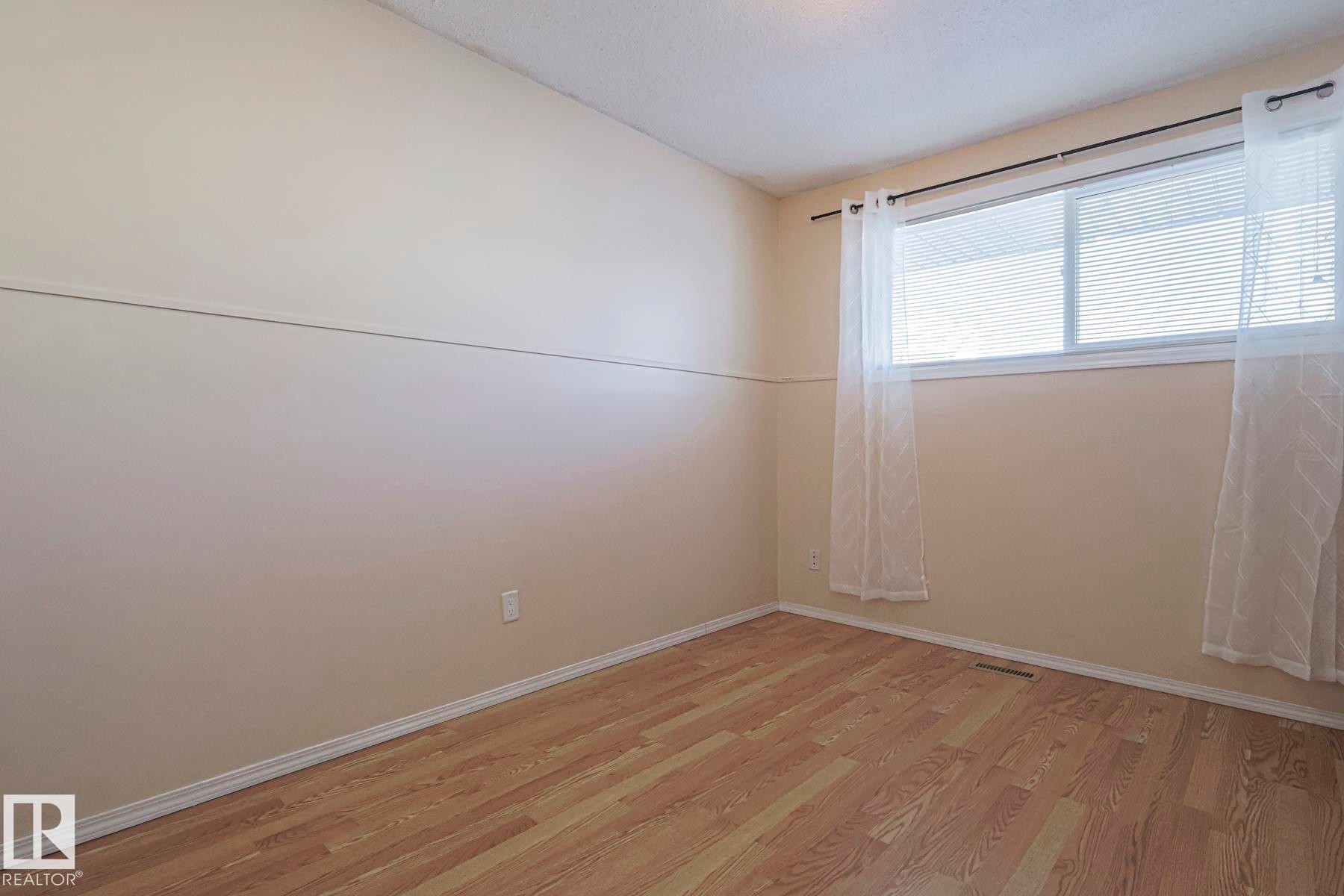 Empty room with light wood-style flooring and a textured ceiling - 1526 69 Street Nw, Edmonton, AB - Indoor Photo Showing Other Room