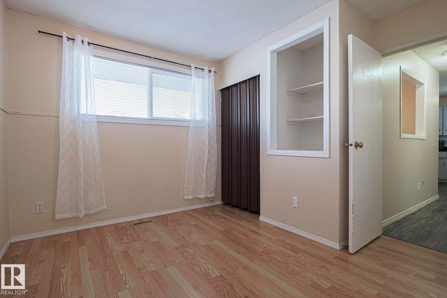 Unfurnished bedroom with light wood-style floors and a textured ceiling - 1526 69 Street Nw, Edmonton, AB - Indoor Photo Showing Other Room