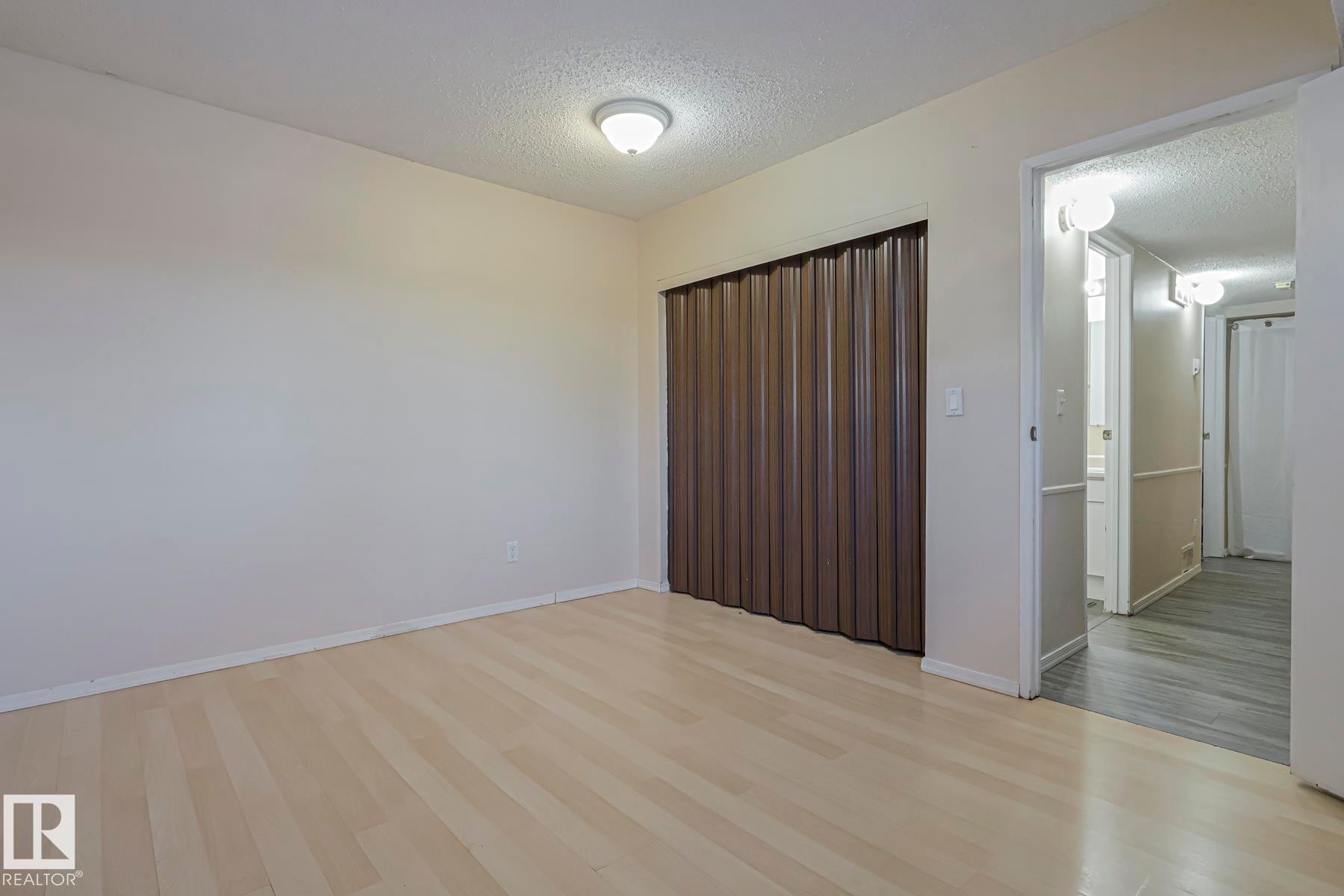 Unfurnished room with a textured ceiling and light wood-style floors - 1526 69 Street Nw, Edmonton, AB - Indoor Photo Showing Other Room