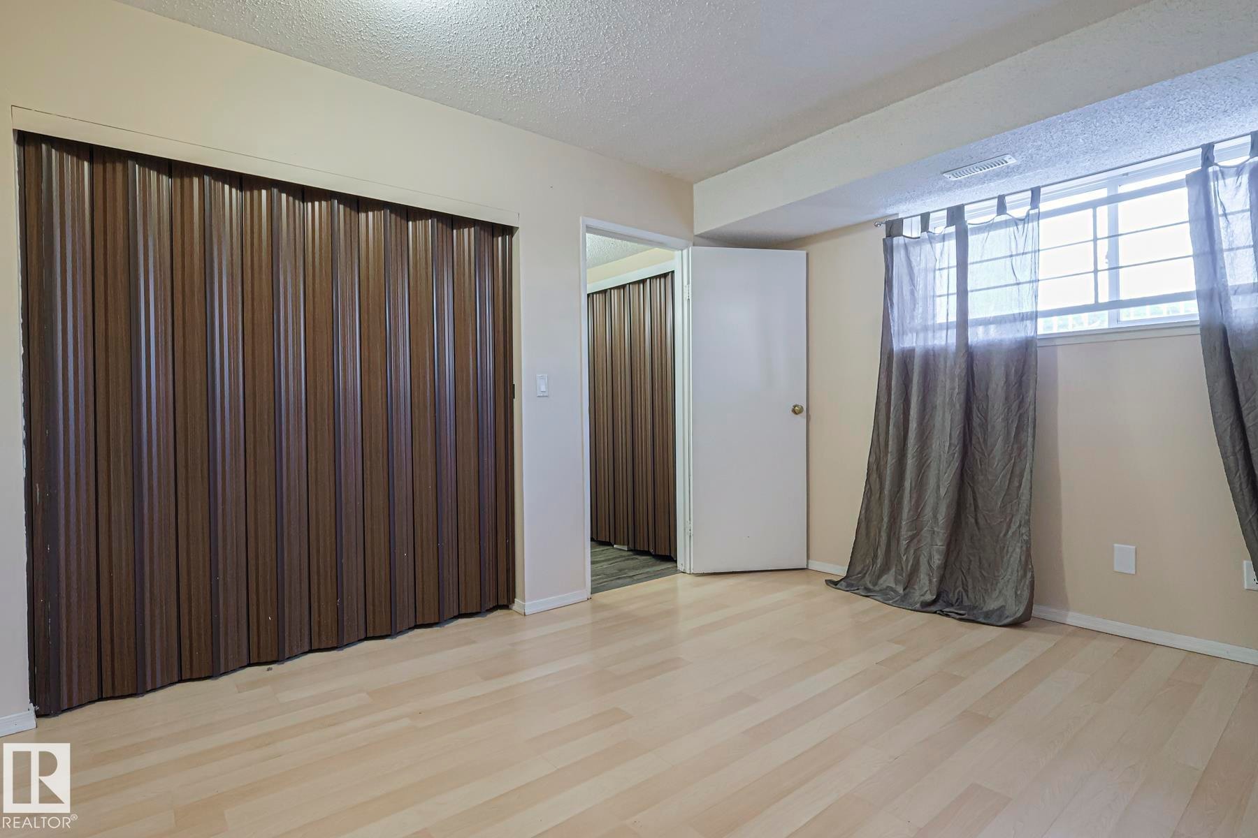 Empty room featuring a textured ceiling and light wood-style flooring - 1526 69 Street Nw, Edmonton, AB - Indoor Photo Showing Other Room