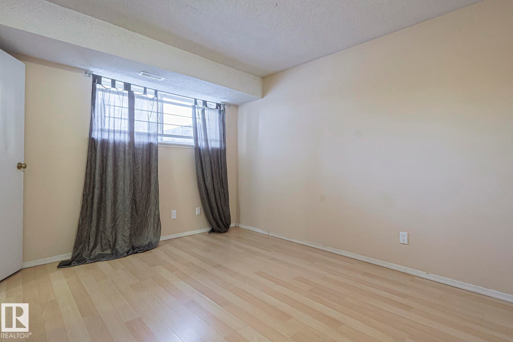 Unfurnished room with light wood finished floors and a textured ceiling - 1526 69 Street Nw, Edmonton, AB - Indoor Photo Showing Other Room