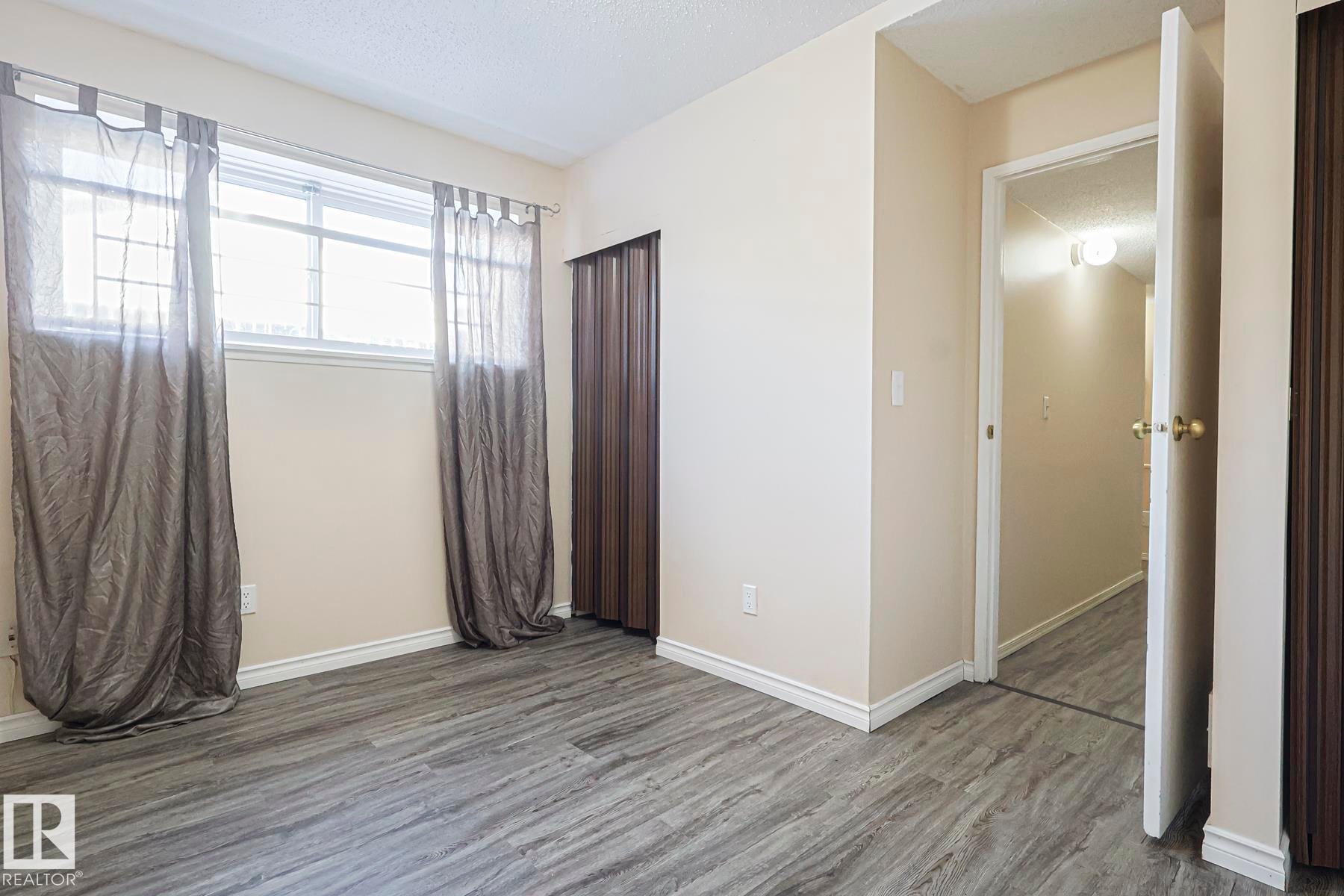 Unfurnished bedroom with a textured ceiling and wood finished floors - 1526 69 Street Nw, Edmonton, AB - Indoor