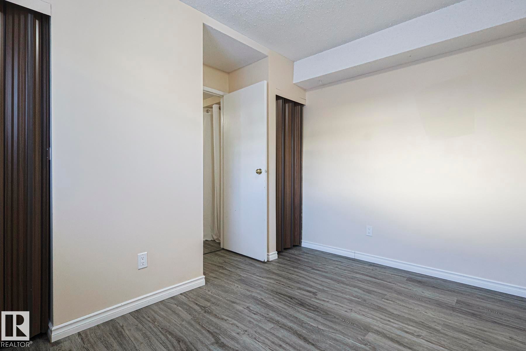 Unfurnished bedroom featuring a textured ceiling and dark wood finished floors - 1526 69 Street Nw, Edmonton, AB - Indoor Photo Showing Other Room