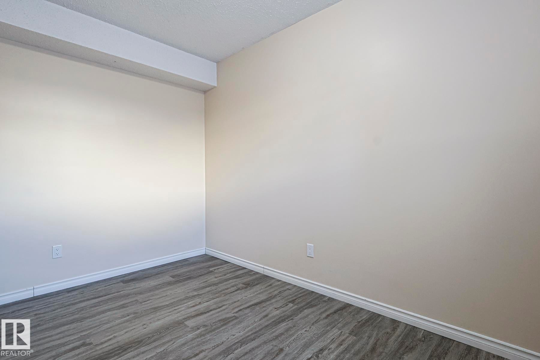 Empty room with dark wood-style floors and a textured ceiling - 1526 69 Street Nw, Edmonton, AB - Indoor Photo Showing Other Room