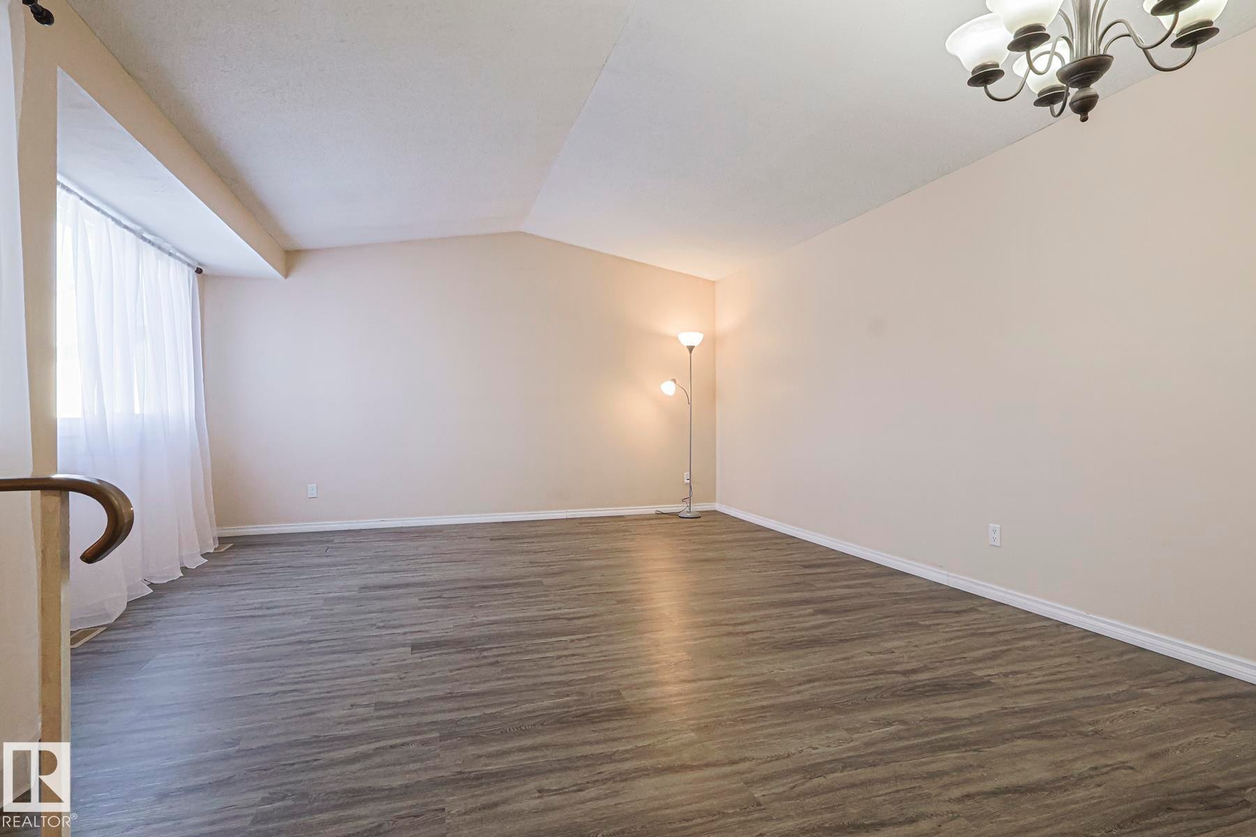 Unfurnished room with vaulted ceiling, dark wood-style flooring, and a chandelier - 1526 69 Street Nw, Edmonton, AB - Indoor Photo Showing Other Room