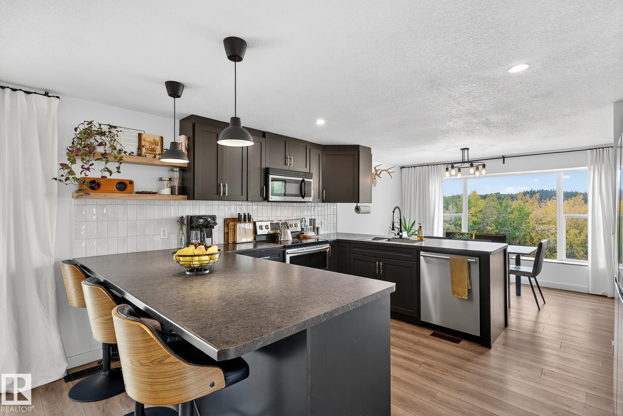 Kitchen featuring a peninsula, dark countertops, and decorative light fixtures - 23509A Twp Road 484, Rural Leduc County, AB - Indoor Photo Showing Kitchen With Upgraded Kitchen