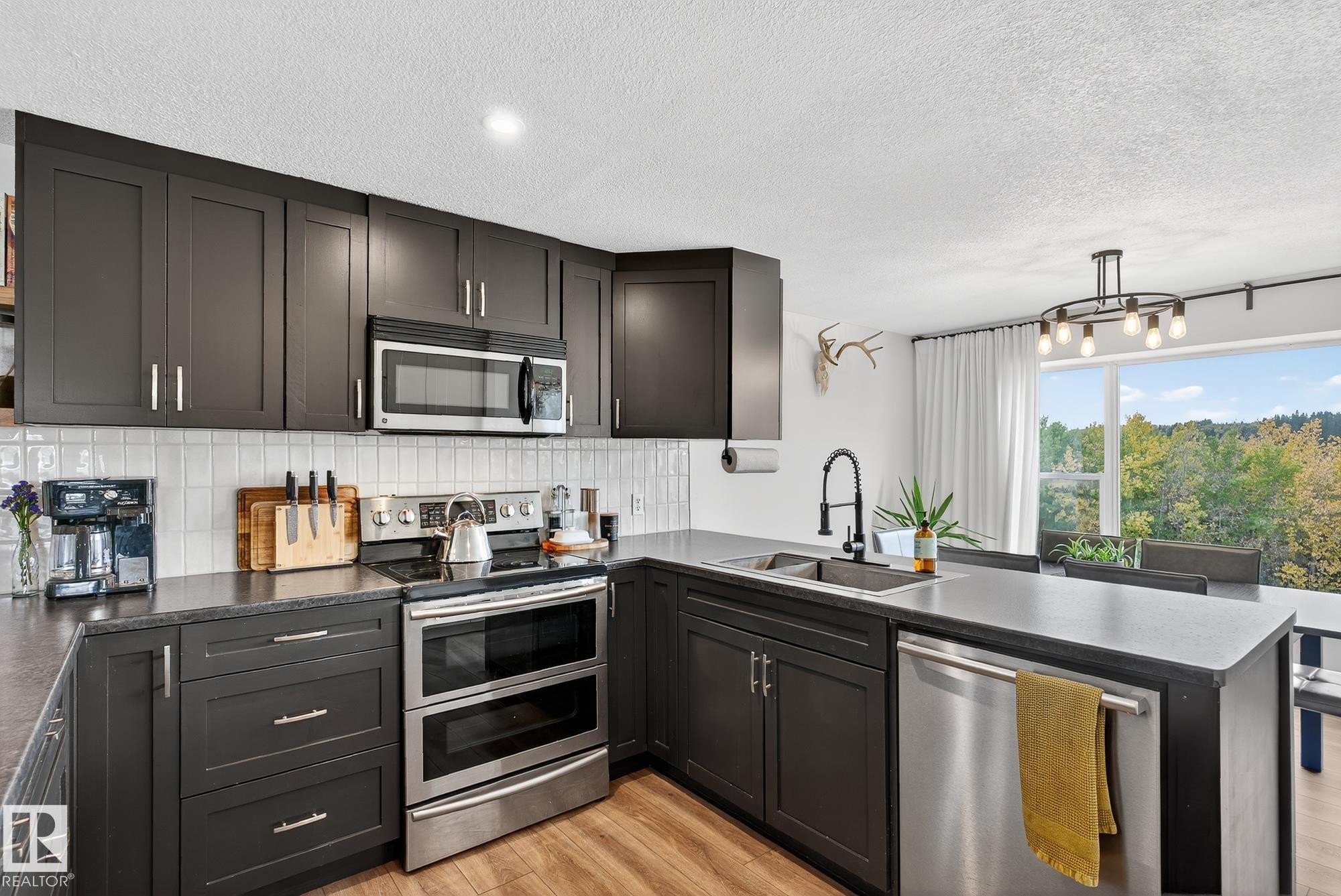 Kitchen featuring stainless steel appliances, a peninsula, pendant lighting, light wood-style floors, and decorative backsplash - 23509A Twp Road 484, Rural Leduc County, AB - Indoor Photo Showing Kitchen With Upgraded Kitchen