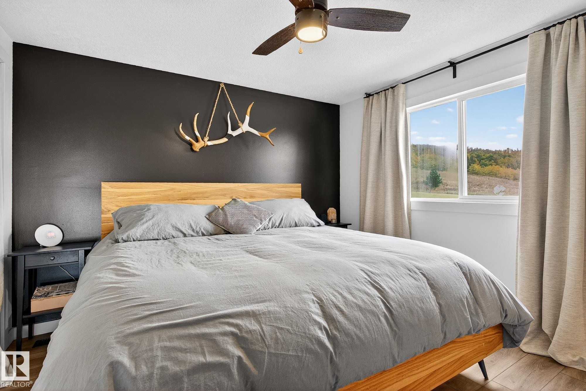 Bedroom featuring wood finished floors, ceiling fan, and an accent wall - 23509A Twp Road 484, Rural Leduc County, AB - Indoor Photo Showing Bedroom