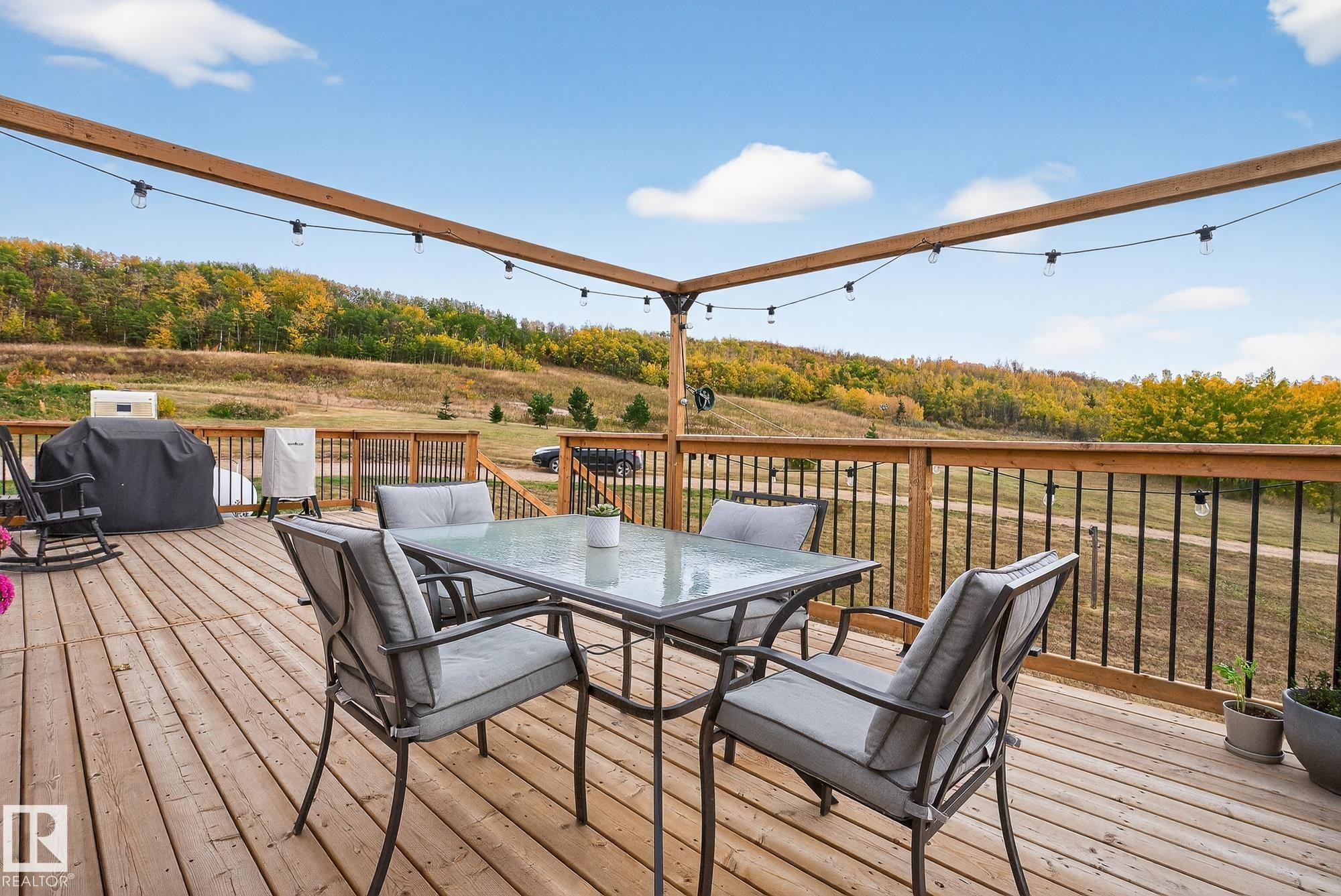 Deck featuring outdoor dining space, a grill, and a view of trees - 23509A Twp Road 484, Rural Leduc County, AB - Outdoor With Deck Patio Veranda With Exterior