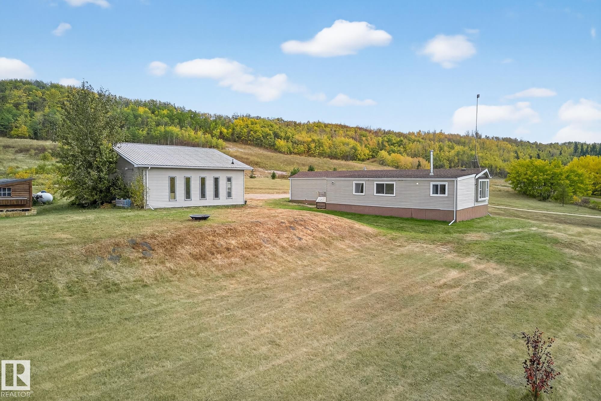 Rear view of property featuring a lawn and a forest view - 23509A Twp Road 484, Rural Leduc County, AB - Outdoor