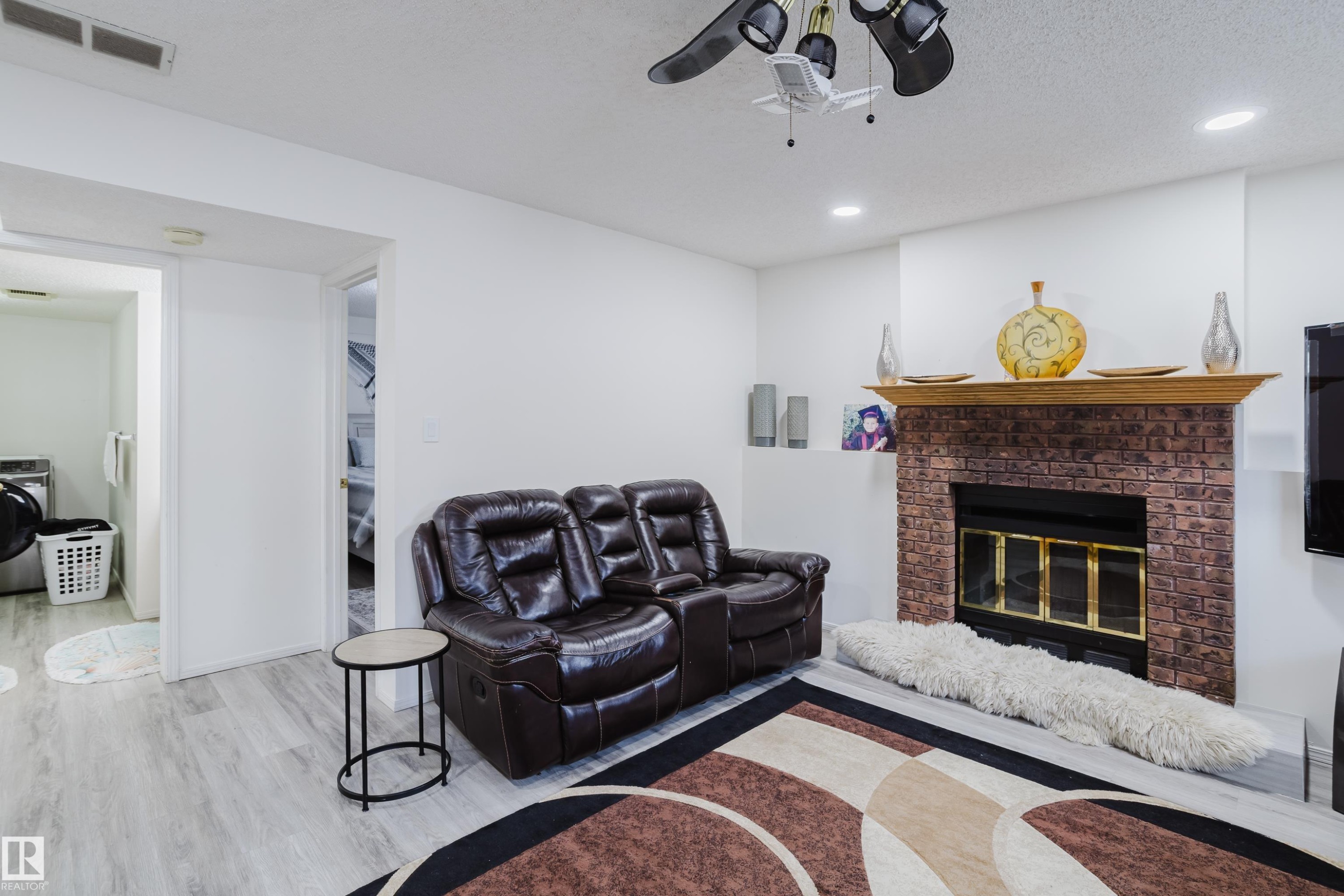 Living room with washer / dryer, a fireplace, wood finished floors, a ceiling fan, and recessed lighting - 236 Lago Lindo Crescent, Edmonton, AB - Indoor Photo Showing Living Room With Fireplace