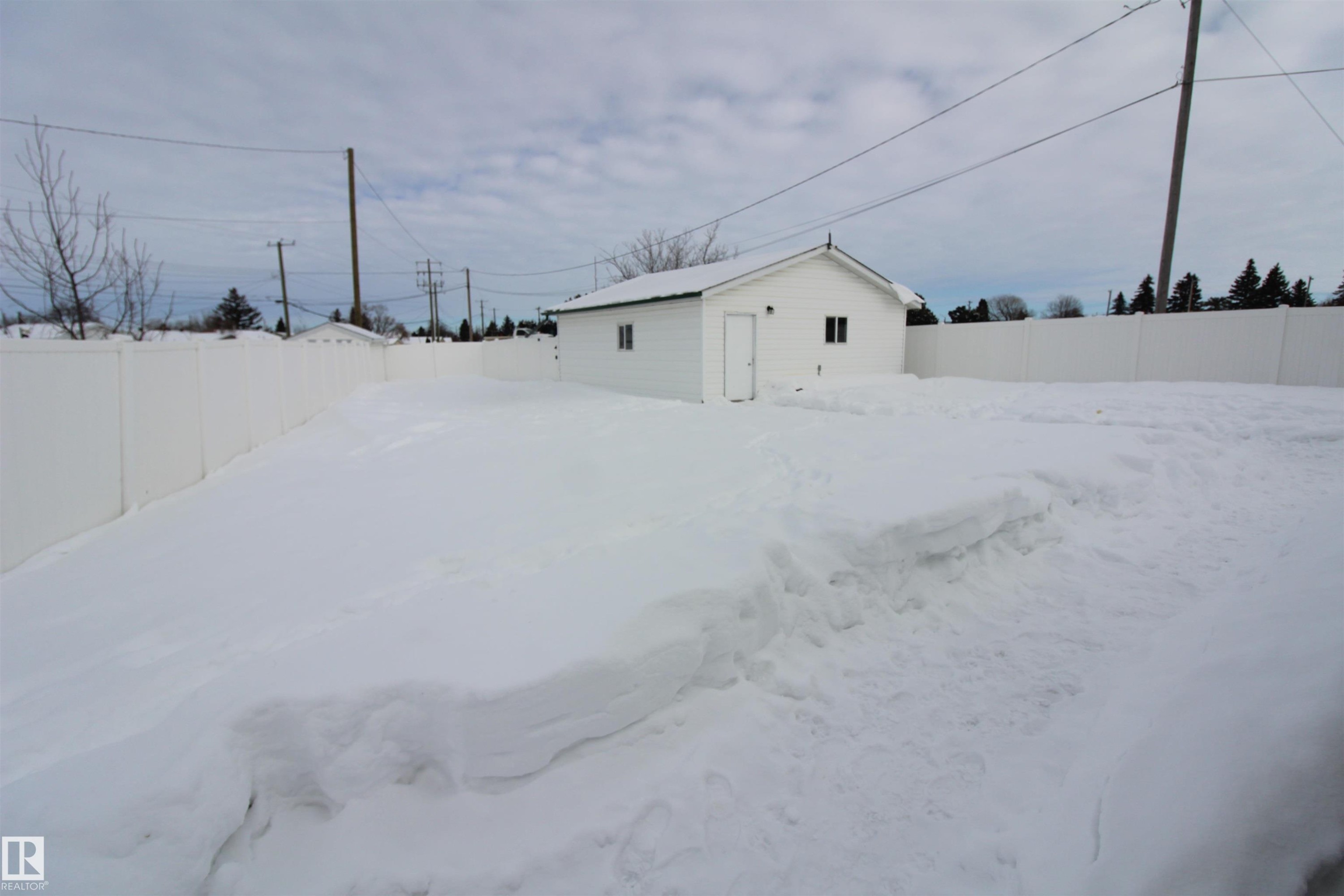 Snowy yard featuring a fenced backyard and an outdoor structure - 10319 106 Ave, Westlock, AB - Outdoor
