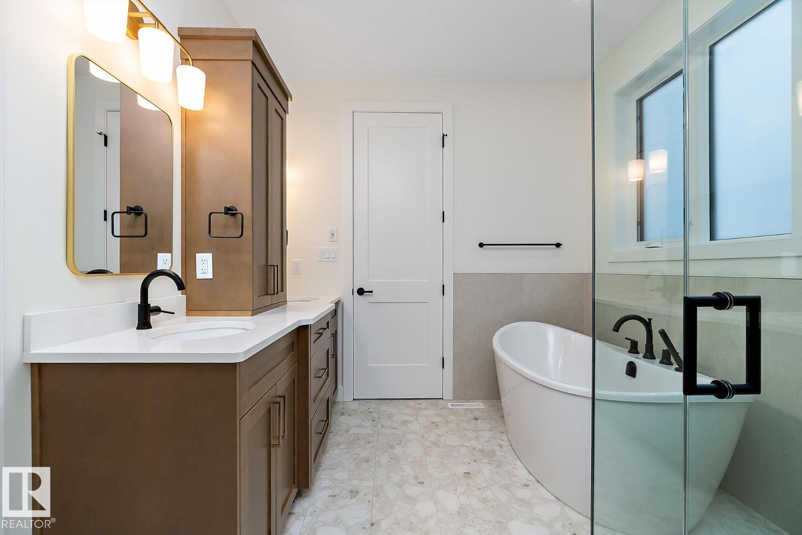 Bathroom featuring double vanity, a freestanding tub, a wainscoted wall, light flooring, and tile walls - 128 Lilac Close, Leduc, AB - Indoor Photo Showing Bathroom