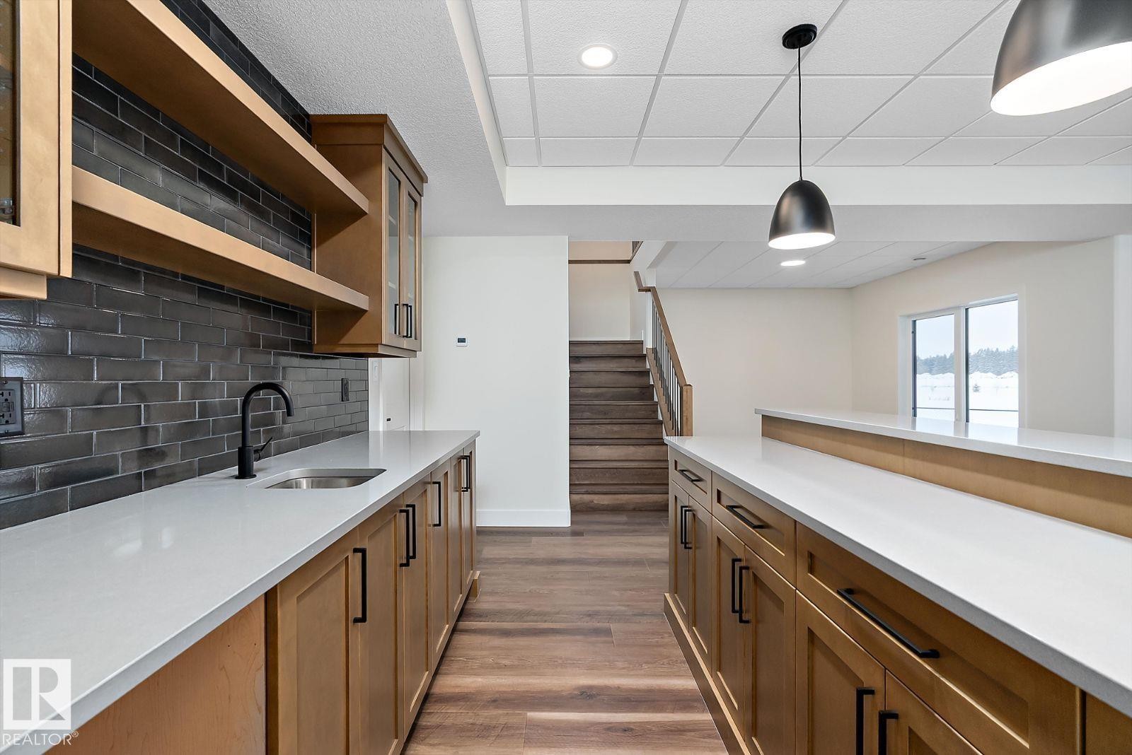Kitchen with wood finish cabinets, open shelves, pendant lighting, light stone countertops, and dark wood-type flooring - 128 Lilac Close, Leduc, AB - Indoor Photo Showing Kitchen
