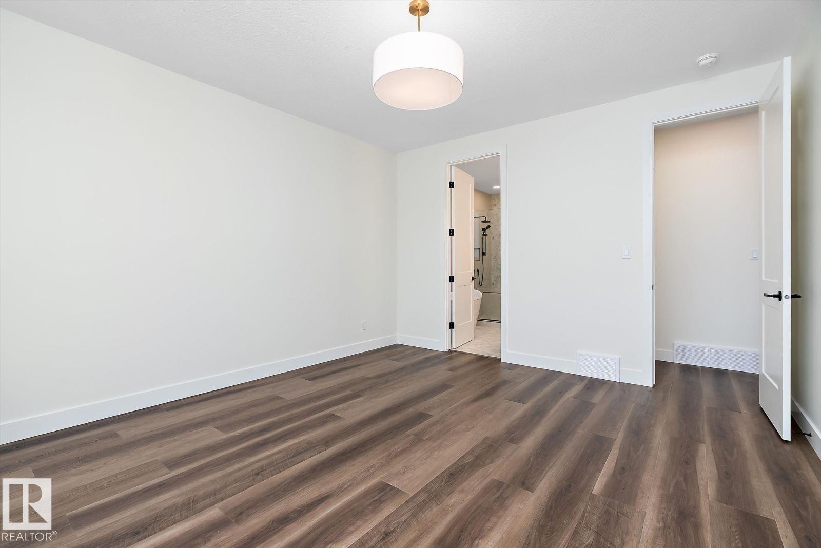Unfurnished bedroom with dark wood-type flooring and ensuite bath - 128 Lilac Close, Leduc, AB - Indoor Photo Showing Other Room