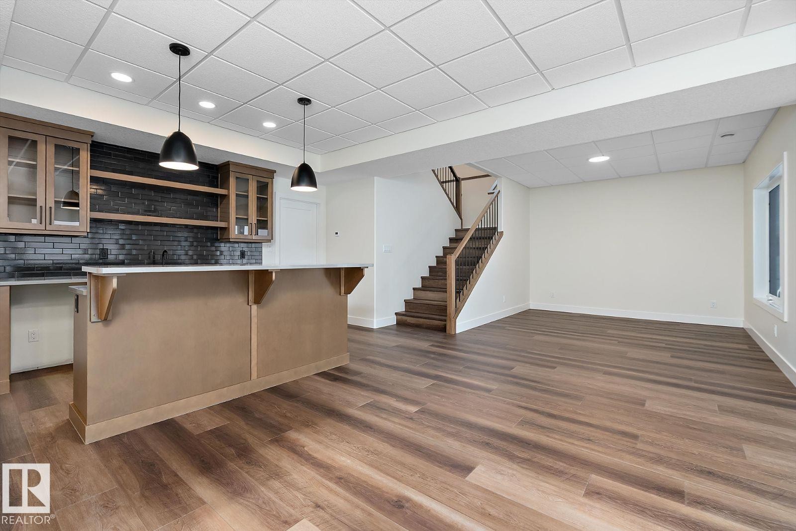 Bar with glass insert cabinets, open shelves, pendant lighting, a paneled ceiling, and backsplash - 128 Lilac Close, Leduc, AB - Indoor Photo Showing Kitchen