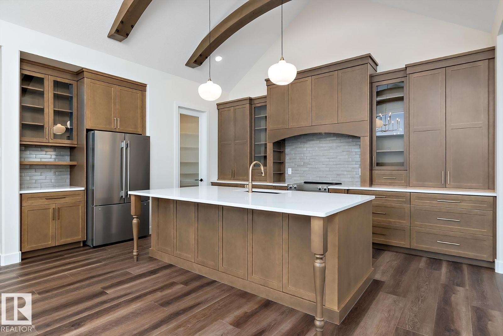 Kitchen featuring glass insert cabinets, vaulted ceiling with beams, freestanding refrigerator, hanging light fixtures, and backsplash - 128 Lilac Close, Leduc, AB - Indoor Photo Showing Kitchen With Upgraded Kitchen