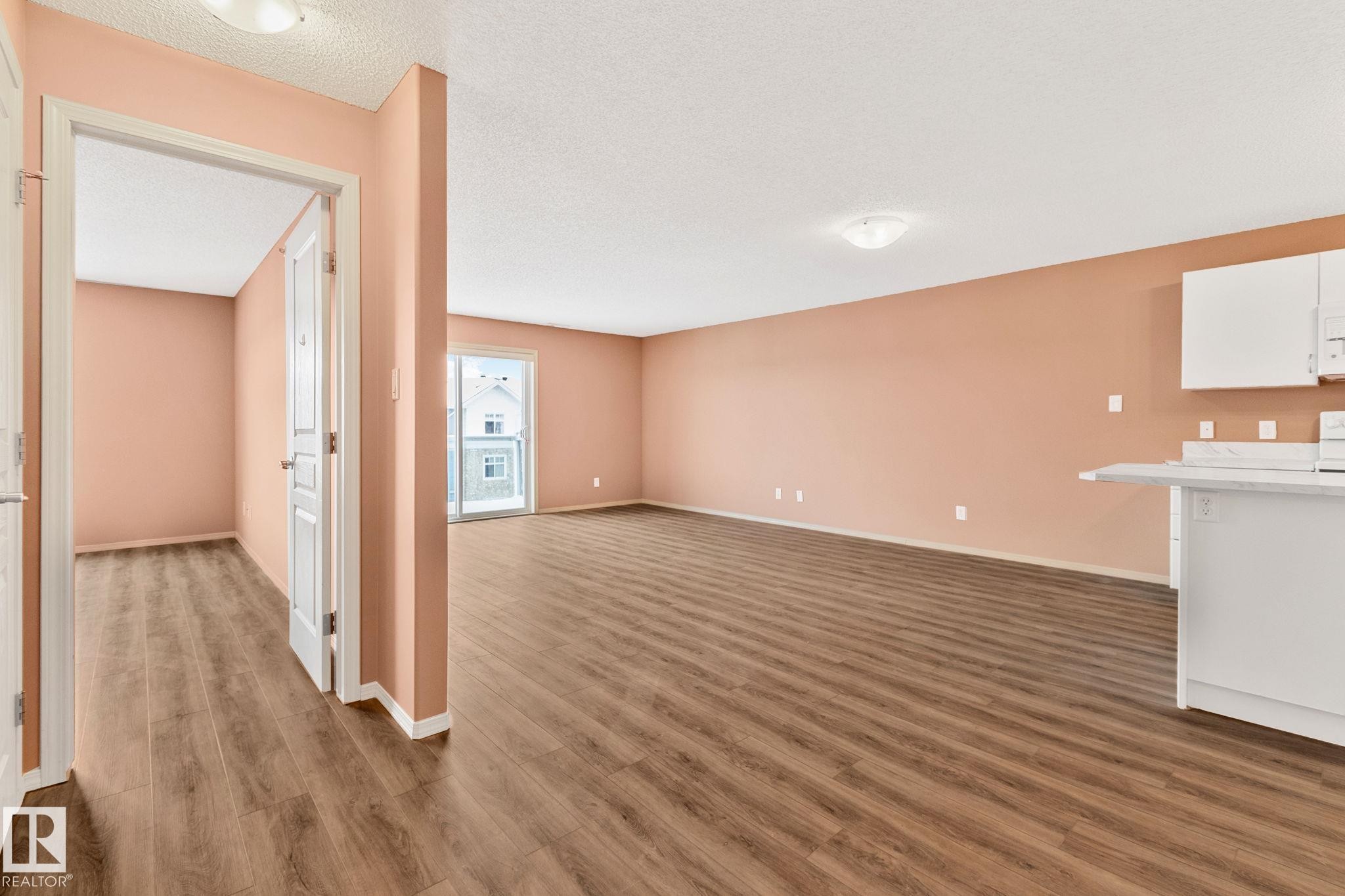 Unfurnished living room with dark wood-style flooring and a textured ceiling - 406 16035 132 Street Nw, Edmonton, AB - Indoor Photo Showing Other Room