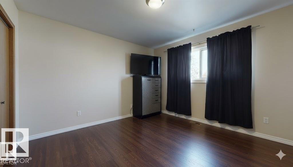 Unfurnished bedroom with wood finished floors and baseboards - 4706 53 St, Leduc, AB - Indoor Photo Showing Other Room