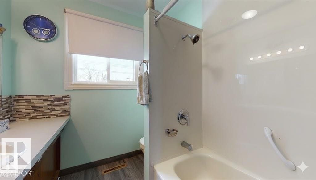 Bathroom featuring vanity, washtub / shower combination, and dark wood-style flooring - 4706 53 St, Leduc, AB - Indoor Photo Showing Bathroom