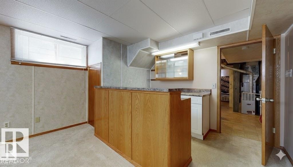 Kitchen featuring light colored carpet, heating unit, and wood finish cabinetry - 4706 53 St, Leduc, AB - Indoor Photo Showing Other Room
