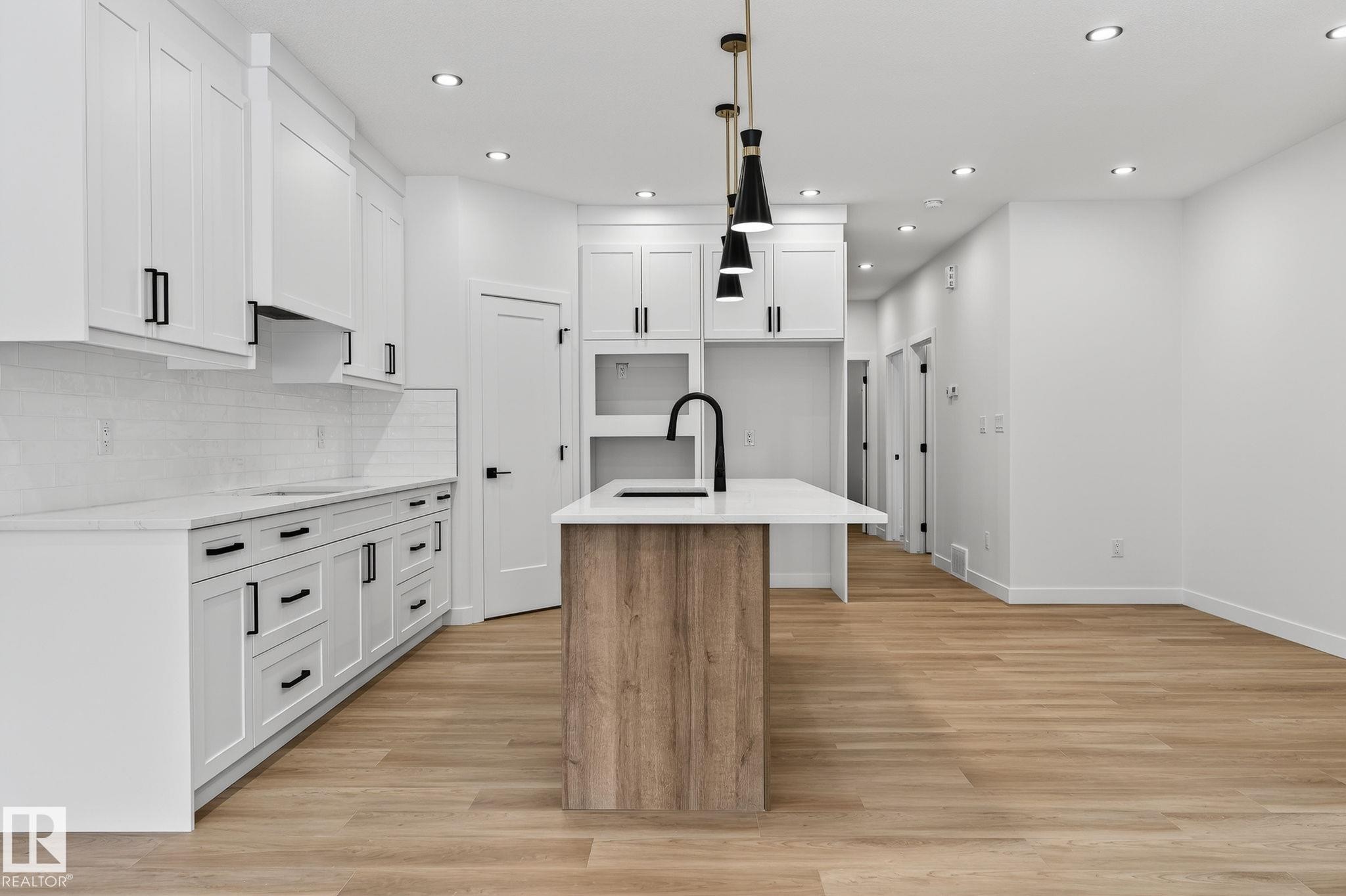 Kitchen featuring two tone cabinets, an island with sink, a breakfast bar, light stone countertops, and light wood-type flooring - 3318 Chickadee Drive, Edmonton, AB - Indoor Photo Showing Kitchen With Upgraded Kitchen