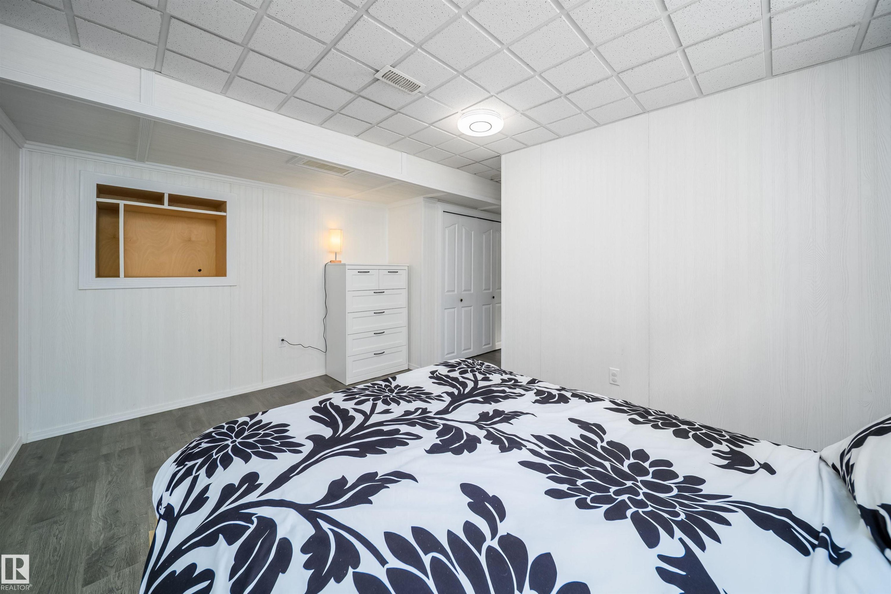 Bedroom with dark wood-style floors, a closet, a paneled ceiling, and wooden walls - 1179 Oakland Drive, Devon, AB - Indoor Photo Showing Bedroom