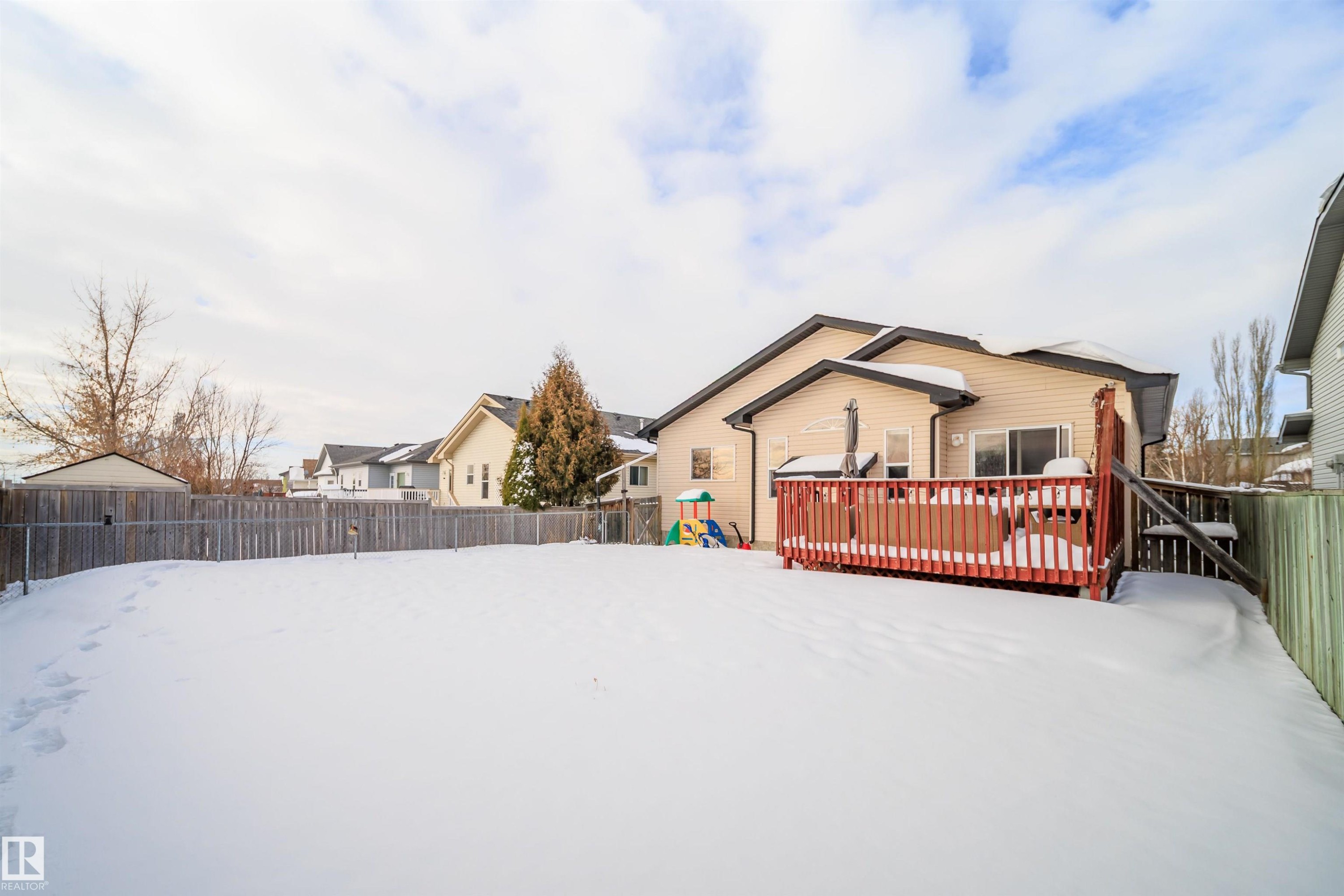 Snow covered rear of property featuring a fenced backyard and a wooden deck - 1179 Oakland Drive, Devon, AB - Outdoor