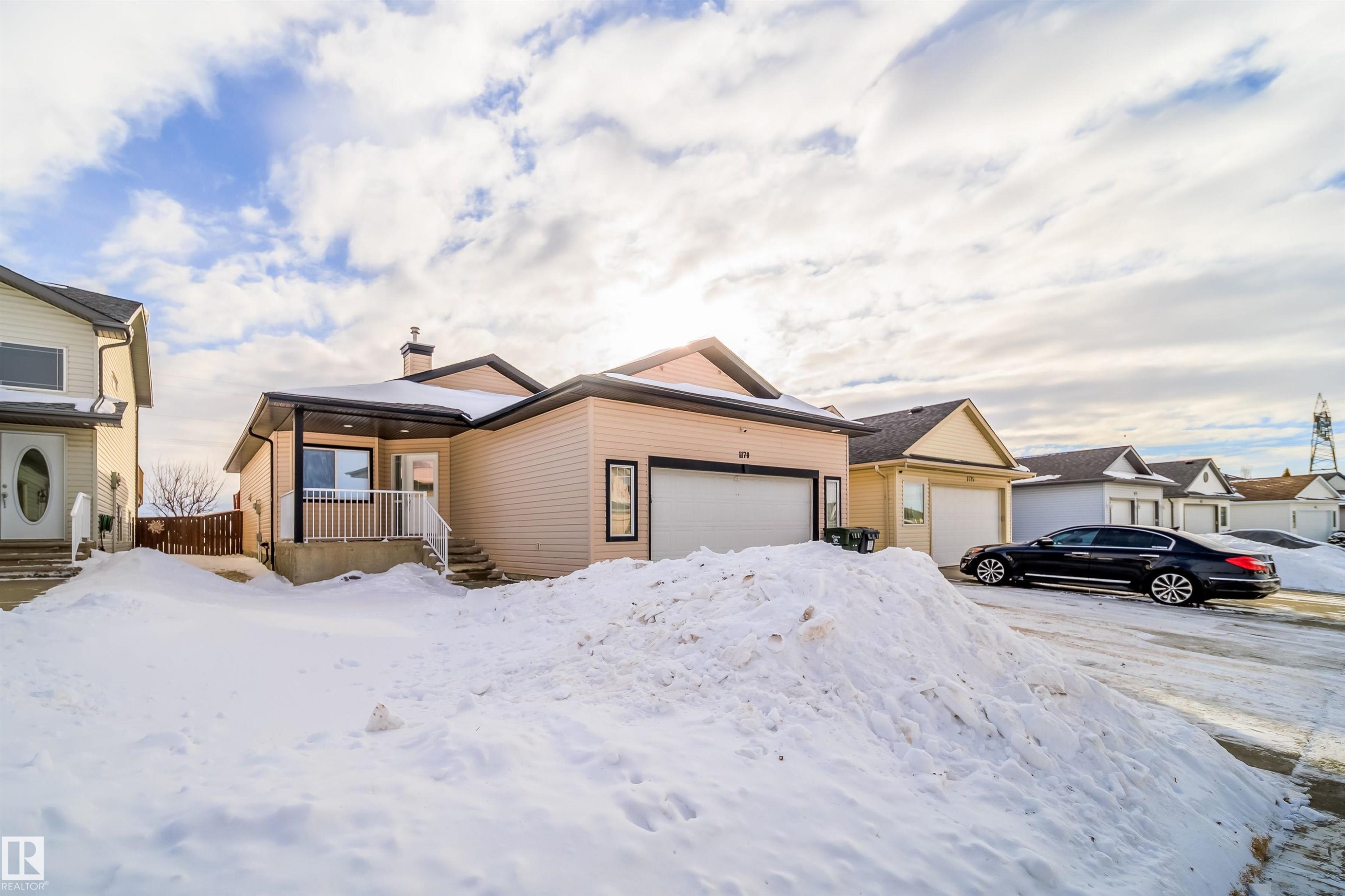 View of front of home featuring an attached garage and a chimney - 1179 Oakland Drive, Devon, AB - Outdoor With Facade