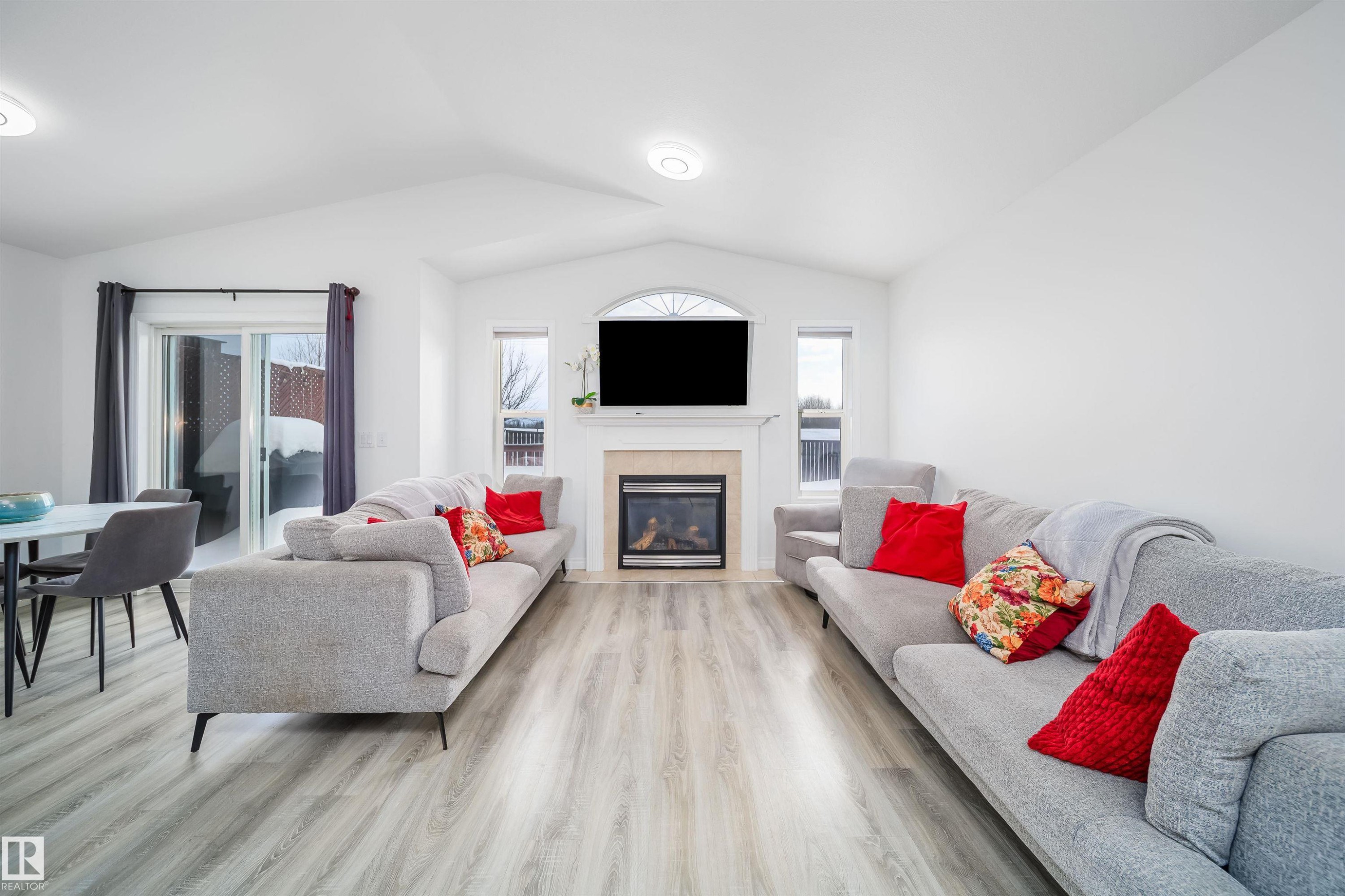Living room featuring healthy amount of natural light, light wood finished floors, and a tiled fireplace - 1179 Oakland Drive, Devon, AB - Indoor Photo Showing Living Room With Fireplace