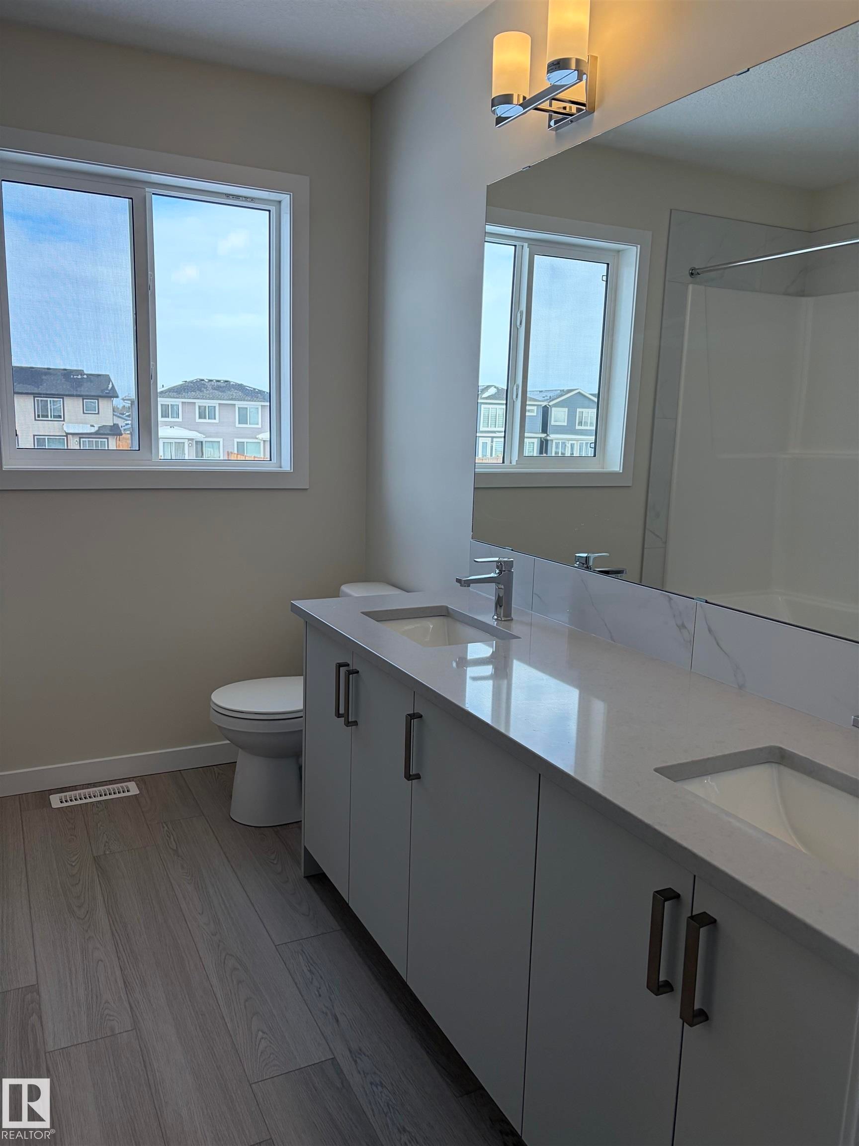 Bathroom with double vanity, light wood-style flooring, and a shower - 5756 Hawthorn Common, Edmonton, AB - Indoor Photo Showing Bathroom