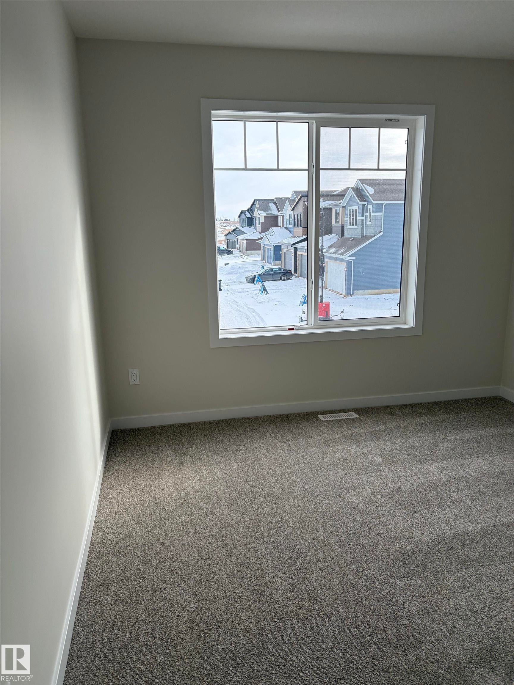 Empty room featuring carpet flooring, plenty of natural light, and a residential view - 5756 Hawthorn Common, Edmonton, AB - Indoor Photo Showing Other Room