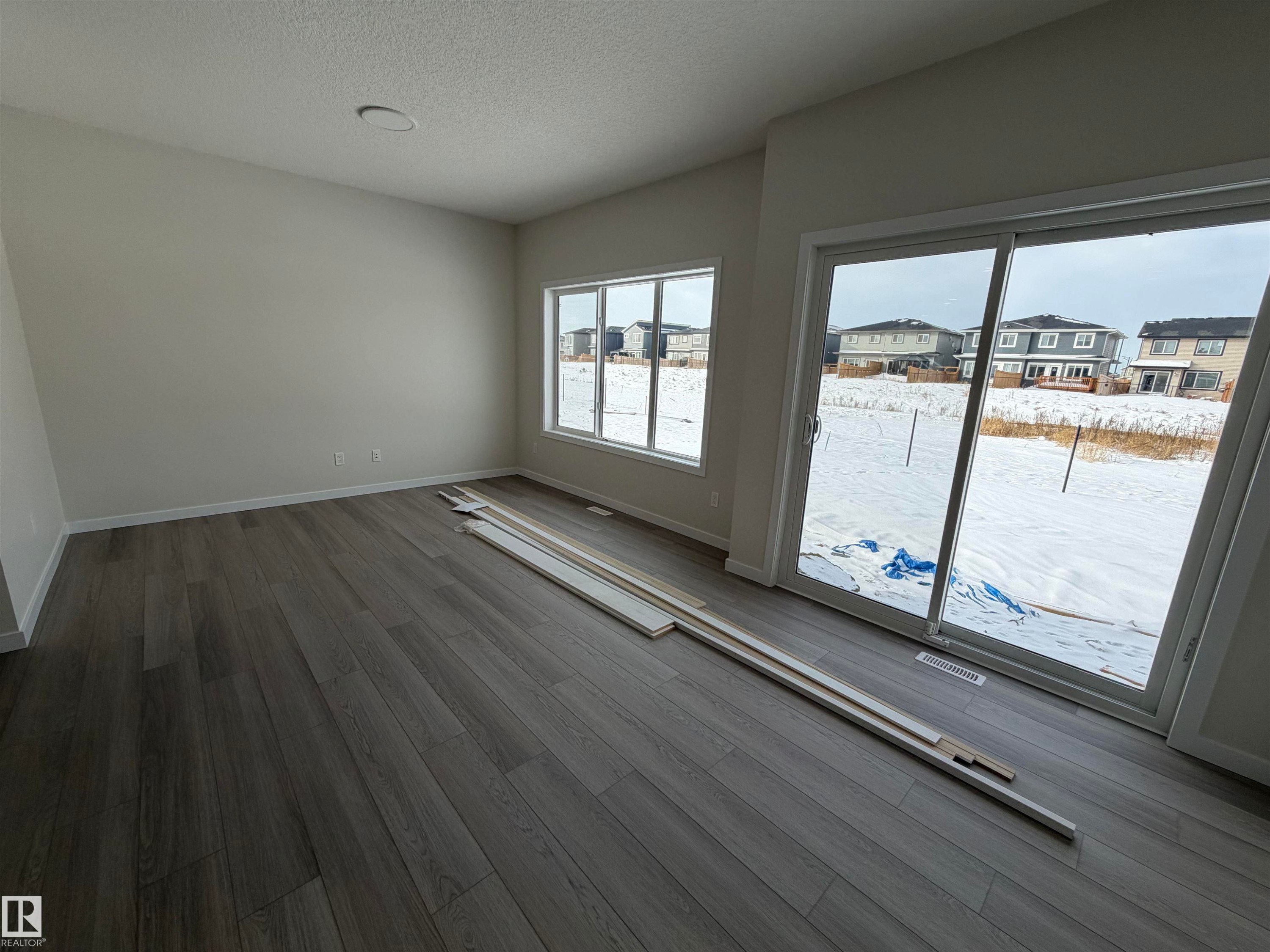 Unfurnished room featuring a residential view, wood finished floors, and a textured ceiling - 5756 Hawthorn Common, Edmonton, AB - Indoor Photo Showing Other Room
