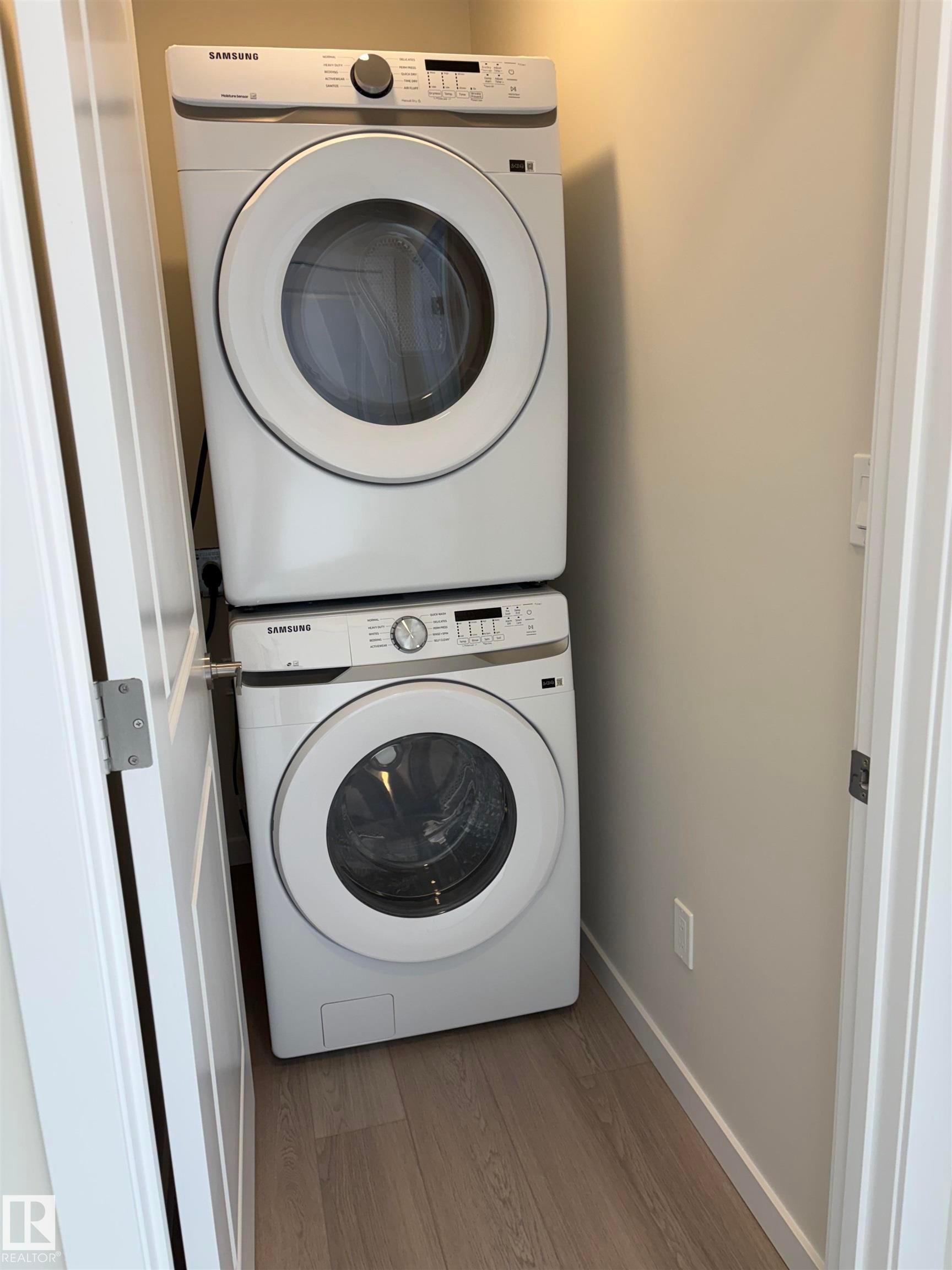 Laundry room featuring light wood-style flooring and stacked washer / drying machine - 5756 Hawthorn Common, Edmonton, AB - Indoor Photo Showing Laundry Room