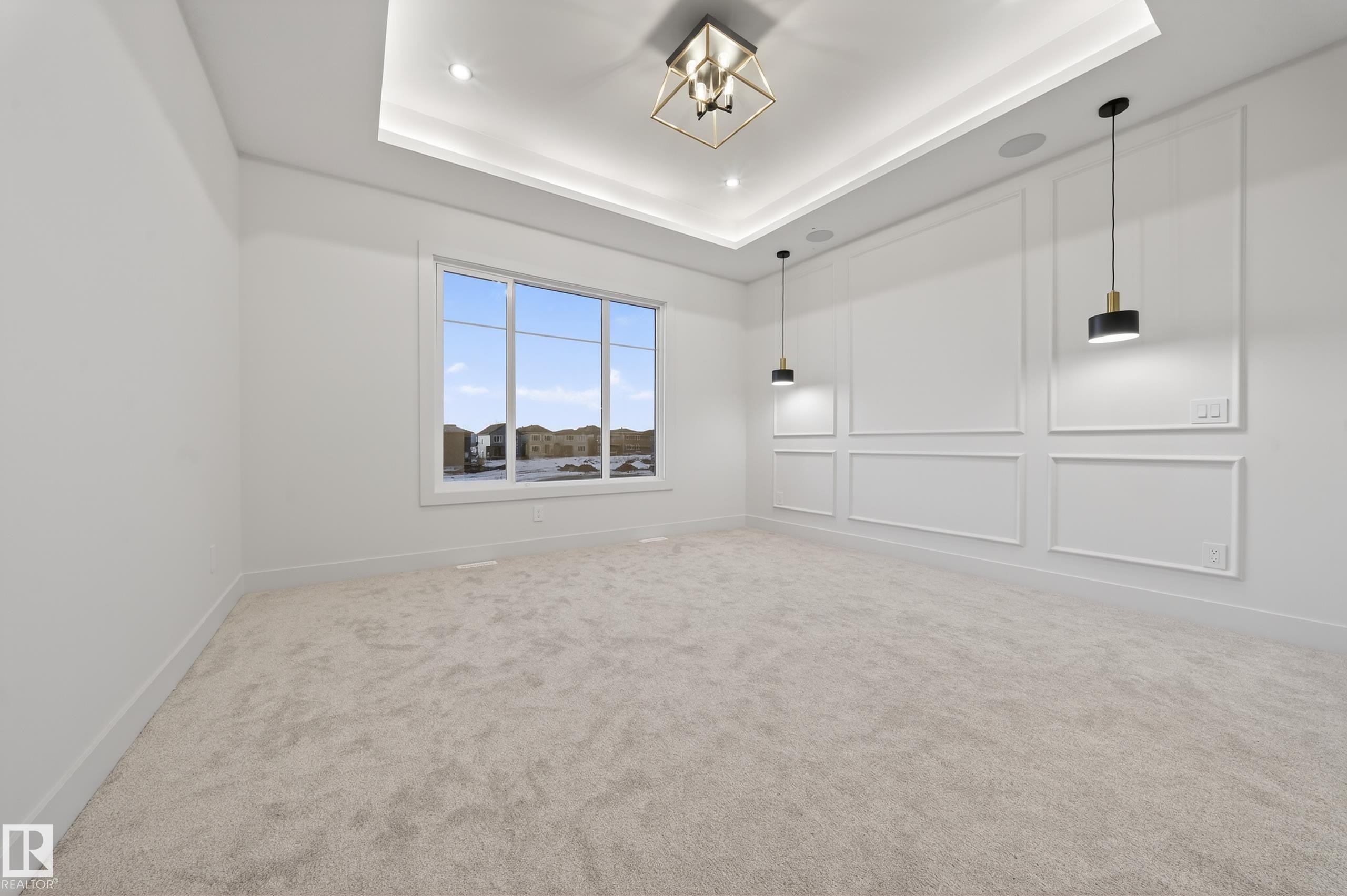 Carpeted spare room with a decorative wall, suspended lighting, and a tray ceiling - 4276 Charles Close, Edmonton, AB - Indoor Photo Showing Other Room
