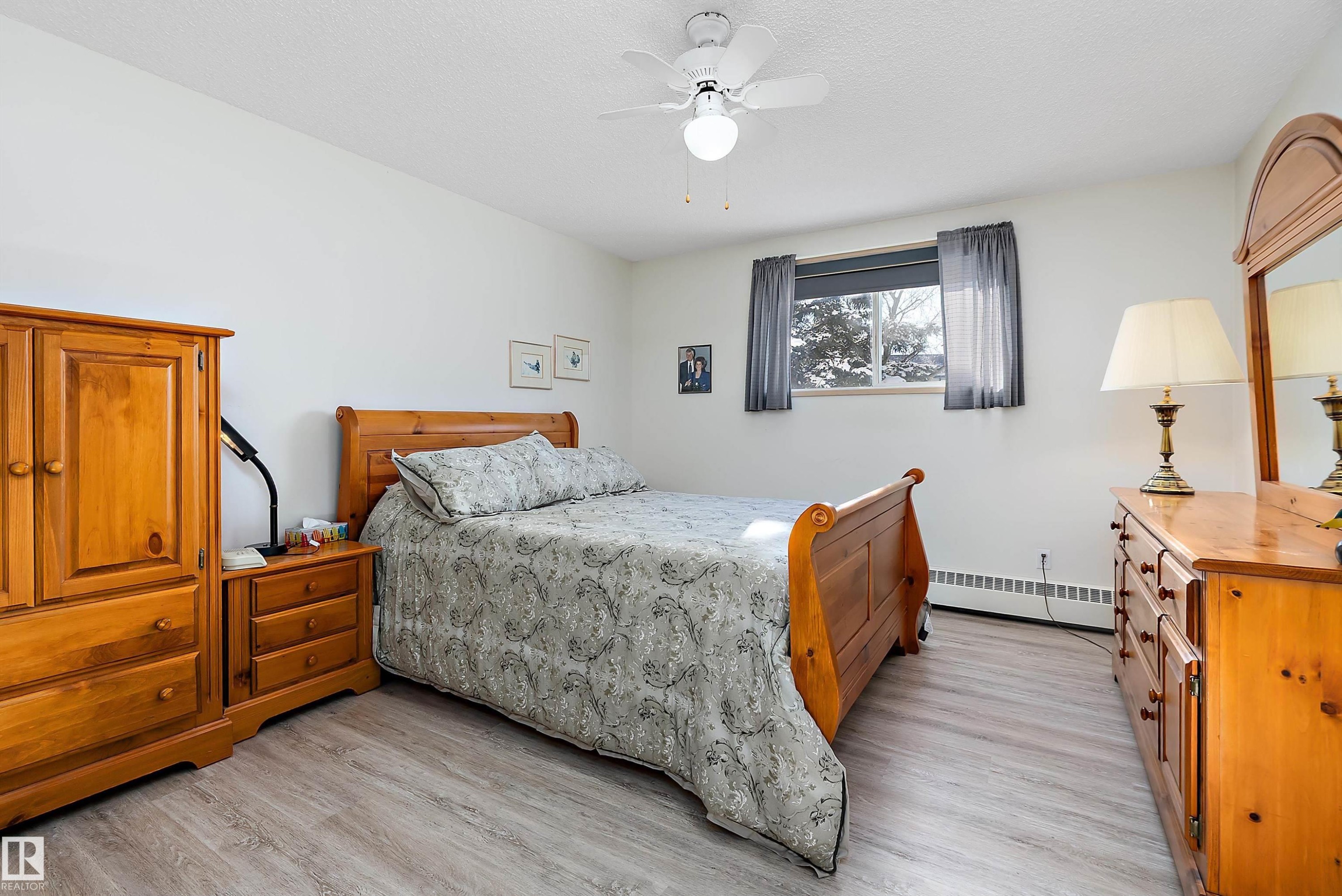 Bedroom featuring baseboard heating, a ceiling fan, and light wood-type flooring - 116 11620 9A Avenue, Edmonton, AB - Indoor Photo Showing Bedroom