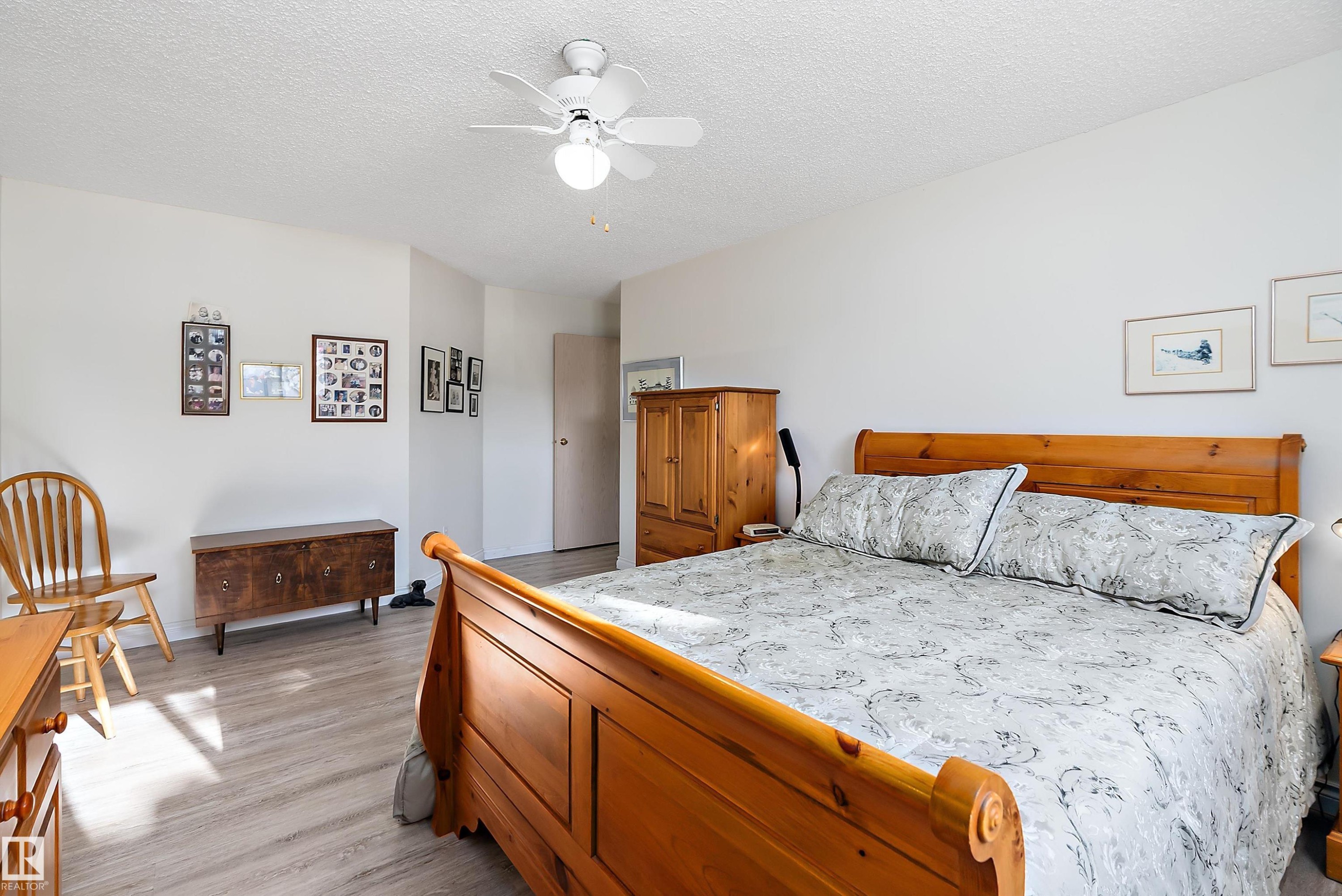 Bedroom with a textured ceiling, light wood-style flooring, and a ceiling fan - 116 11620 9A Avenue, Edmonton, AB - Indoor Photo Showing Bedroom