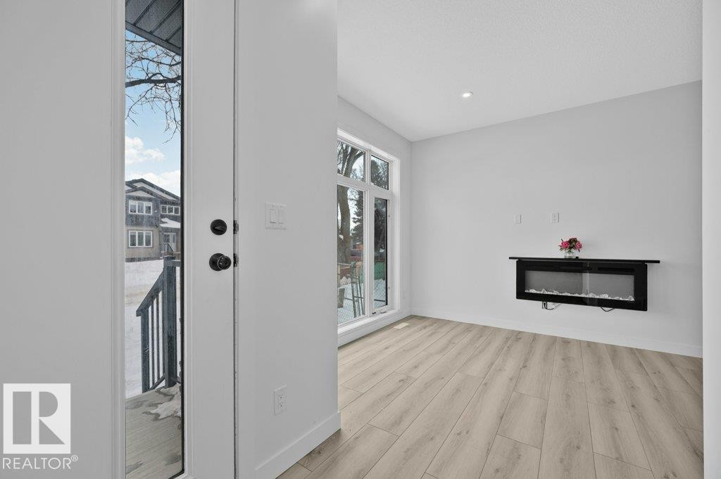 Interior space featuring a glass covered fireplace, light wood-style flooring, and recessed lighting - Edmonton, AB - Indoor With Fireplace