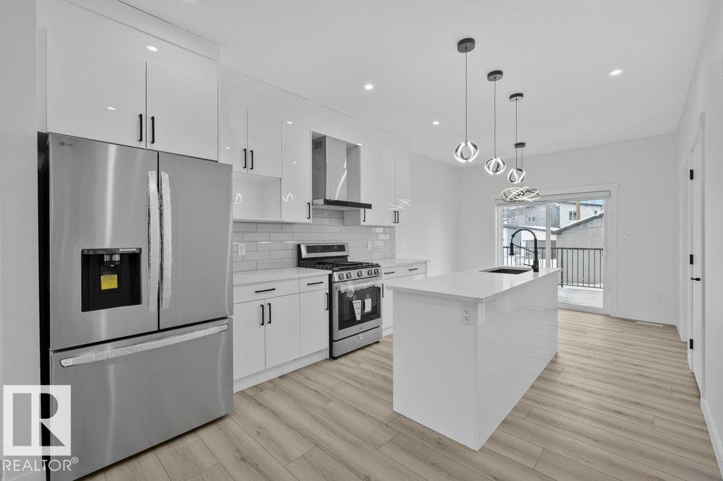 Kitchen featuring stainless steel appliances, a center island with sink, white cabinets, and backsplash - Edmonton, AB - Indoor Photo Showing Kitchen With Upgraded Kitchen
