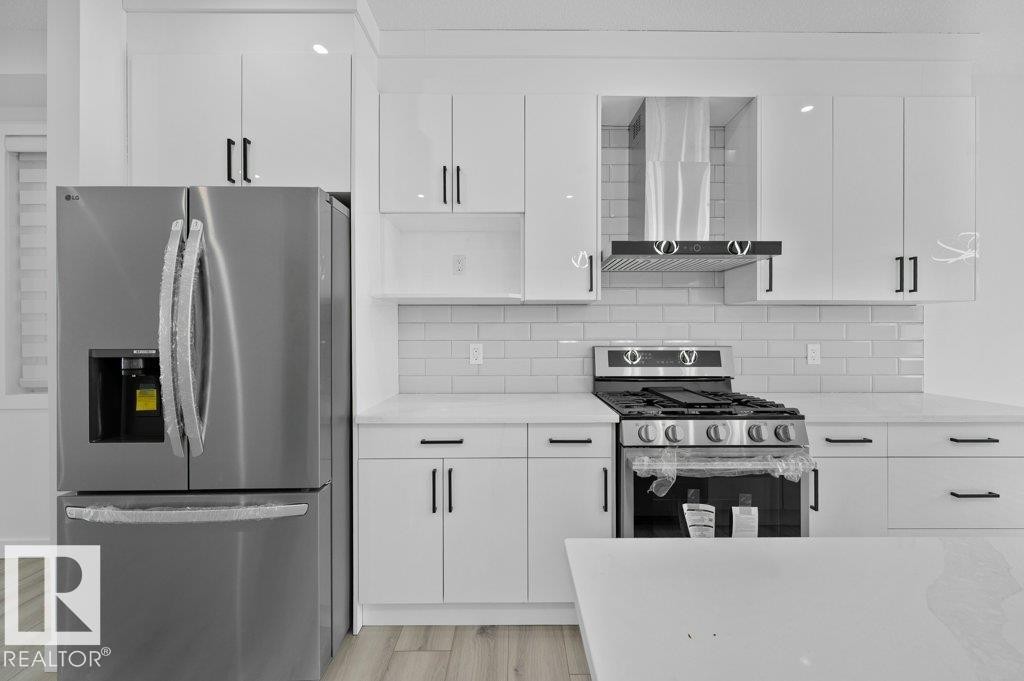 Kitchen featuring stainless steel appliances, white cabinetry, and decorative backsplash - Edmonton, AB - Indoor Photo Showing Kitchen With Upgraded Kitchen