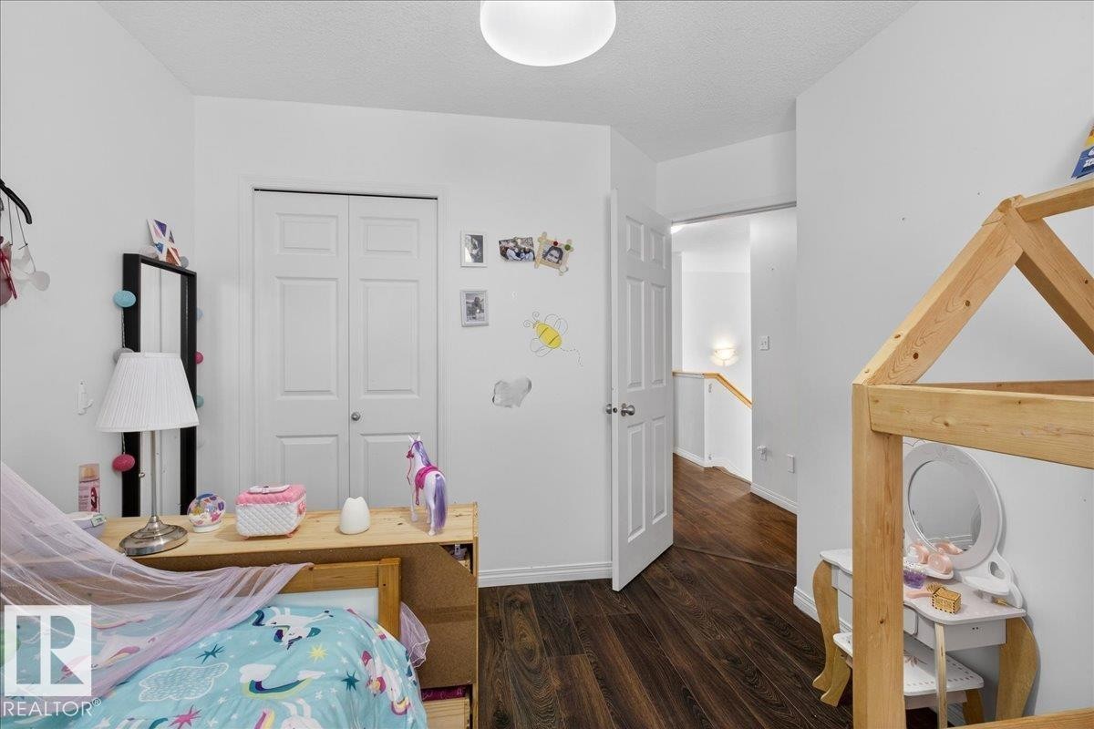 Bedroom with dark wood-style floors, a textured ceiling, and a closet - 4519 Turner Square, Edmonton, AB - Indoor Photo Showing Other Room